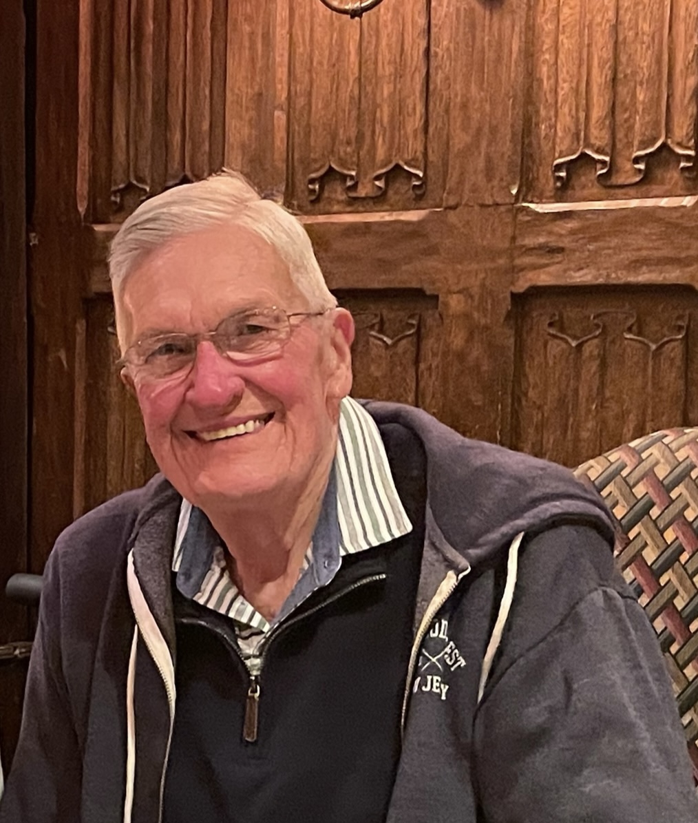 Man with white hair and glasses smiling at camera.