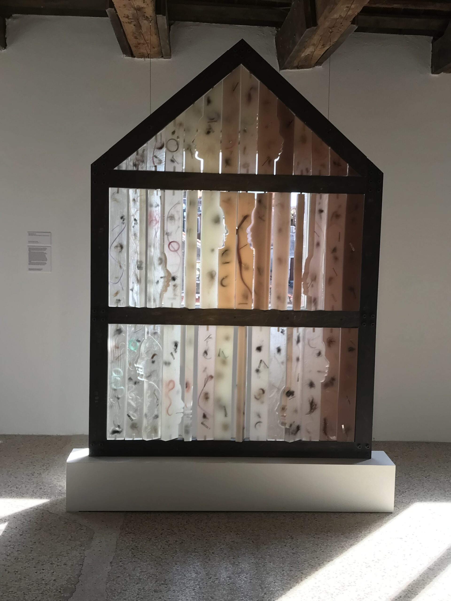 A sculptural installation that looks like the facade of the house. The structure is made up of translucent vertical planks.