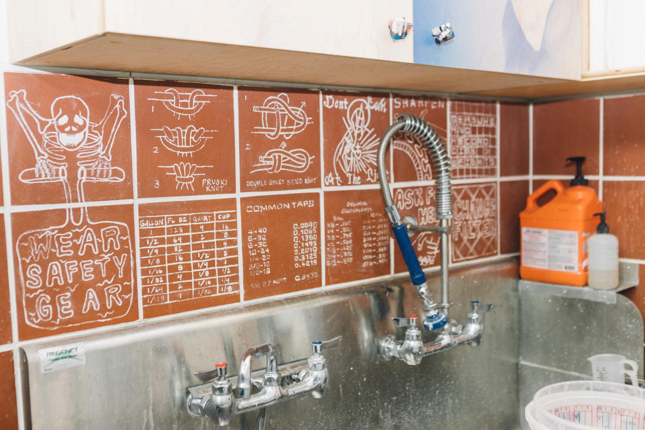 A studio sink with a backsplash of decorated terra cotta tiles