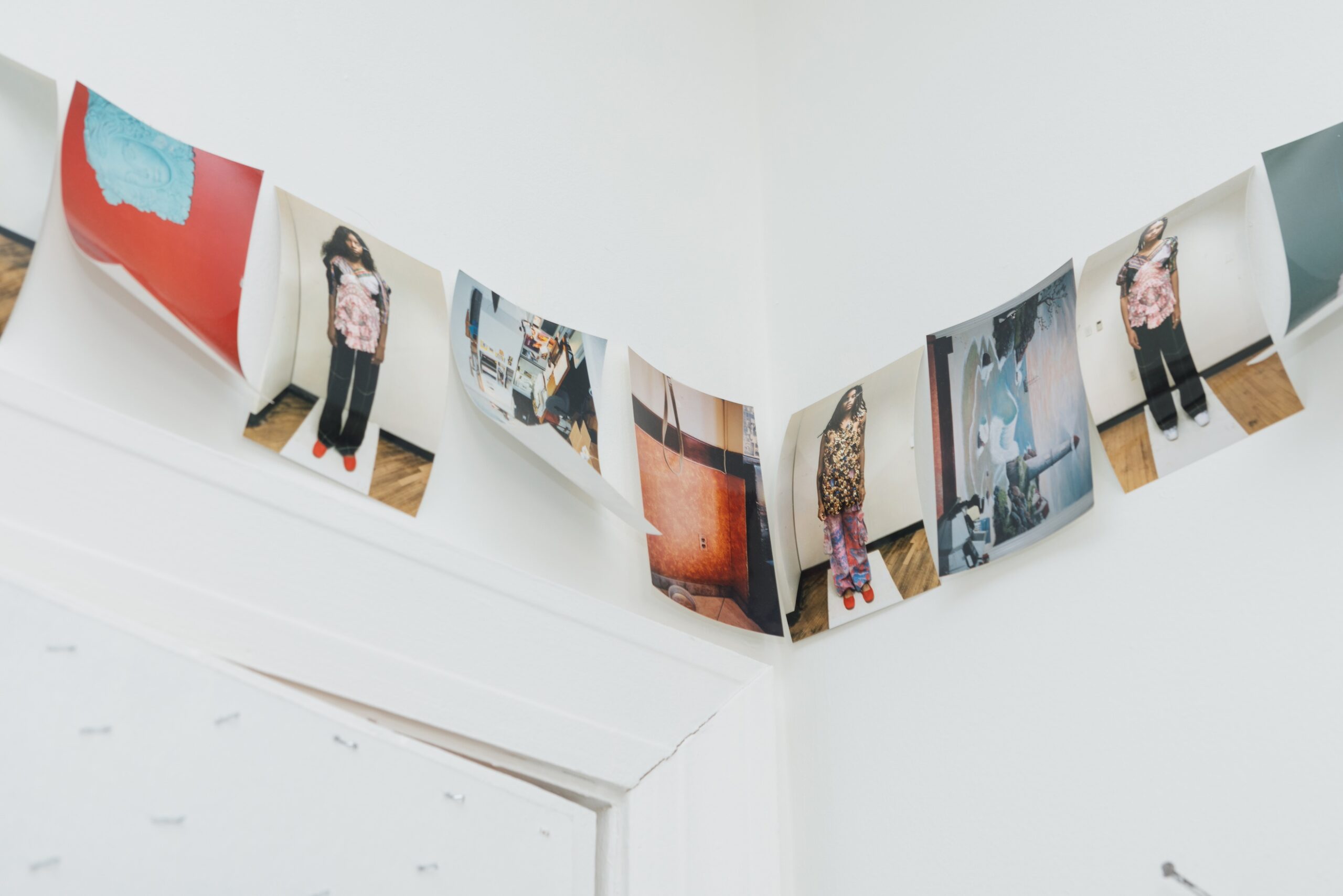 Fashion-fitting photographs pinned up in a row on white walls