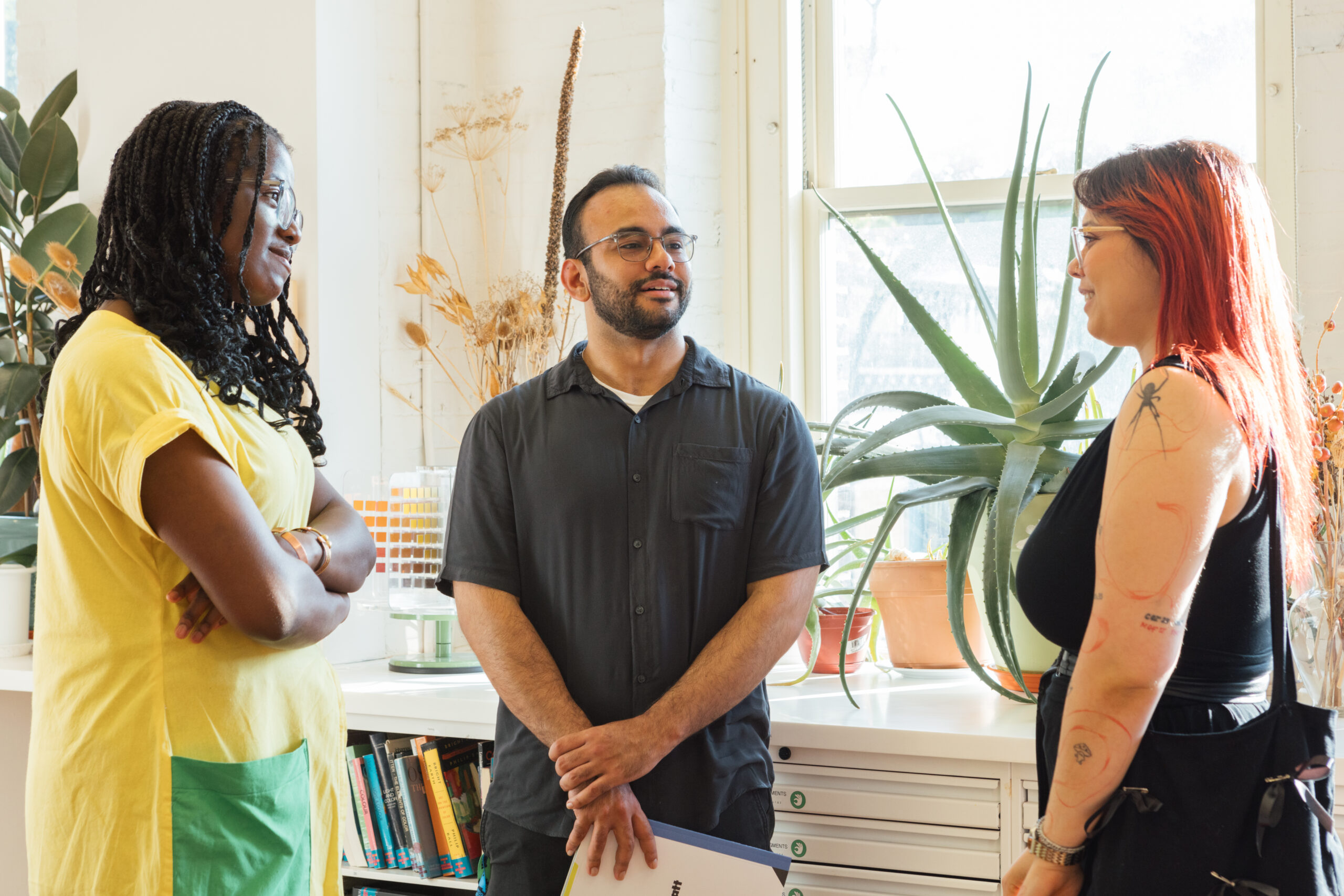 Three people in a bright room standing and conversing