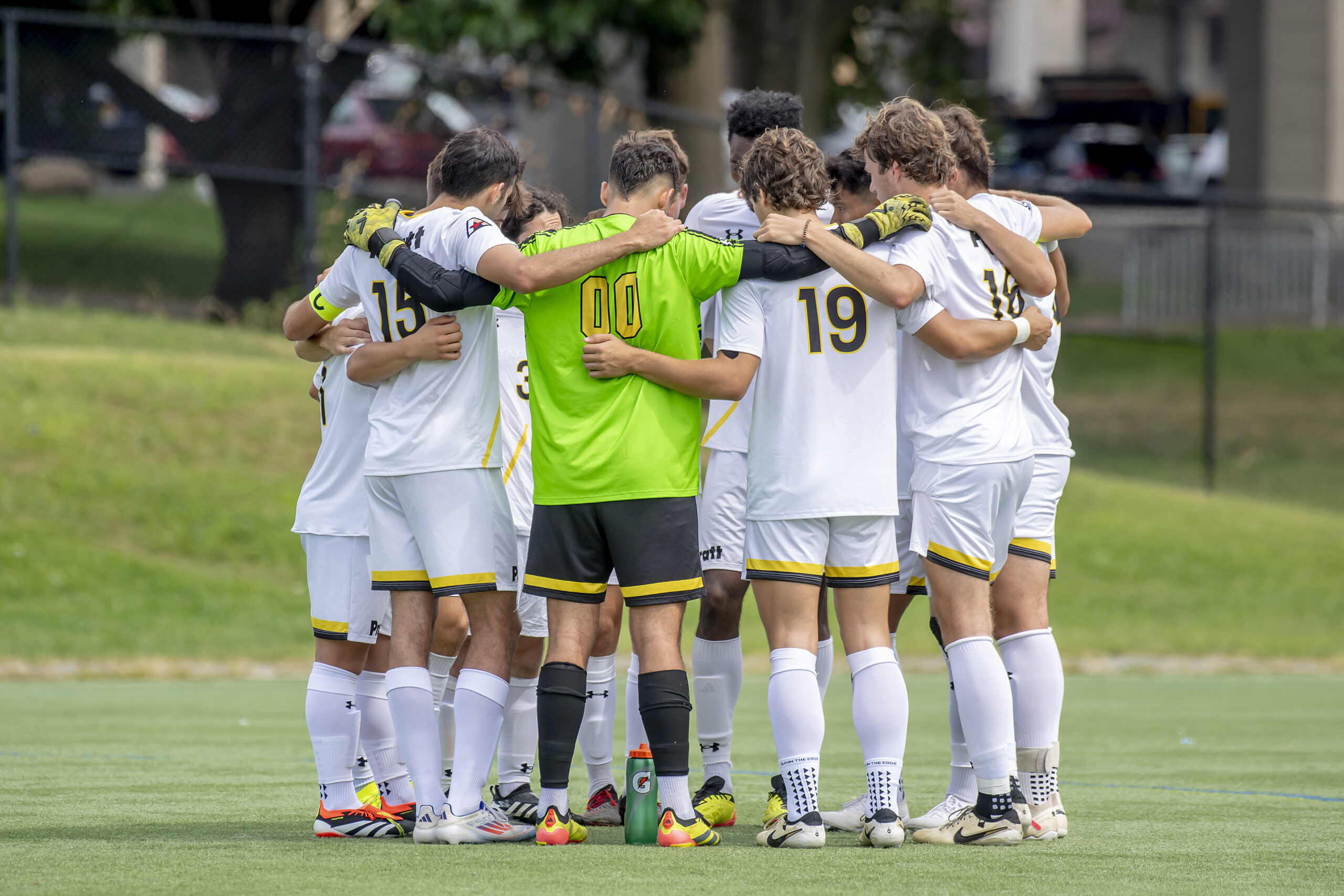A soccer team huddles on a green field
