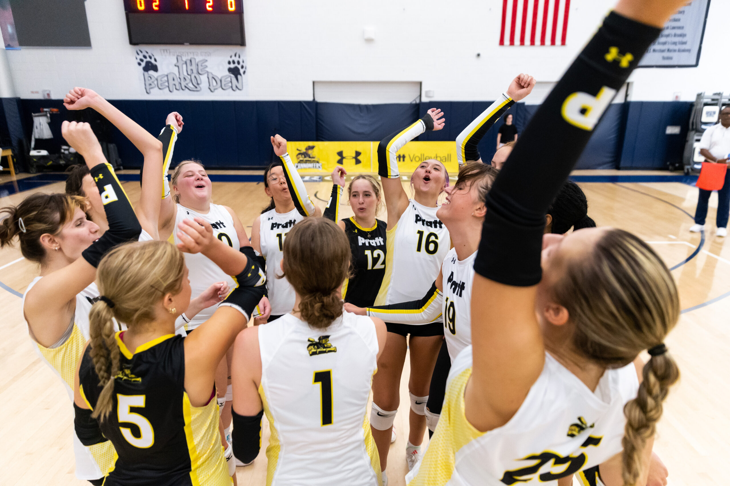 Pratt volleyball players put their arms up and cheer together