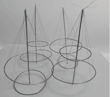 Four cone-like wireframe structures with circular bases and top points connected by vertical strings, forming an abstract model.
