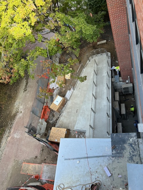 Aerial view of a construction site featuring a concrete ramp and workers in safety gear.