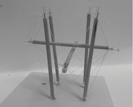 Small tensile structure made from thin sticks and strings, forming a balanced frame held together with visible tension.