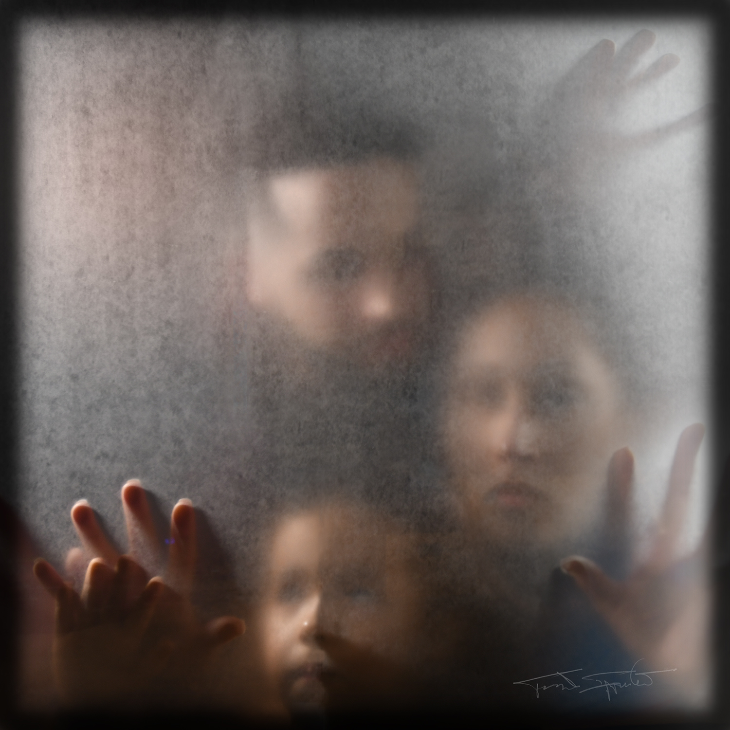 Photographed behind a square pane of frosted glass, a man and a woman press their fingers against the glass. The child near the bottom of the image looks upward, their hand gently clasped against the glass by the man.