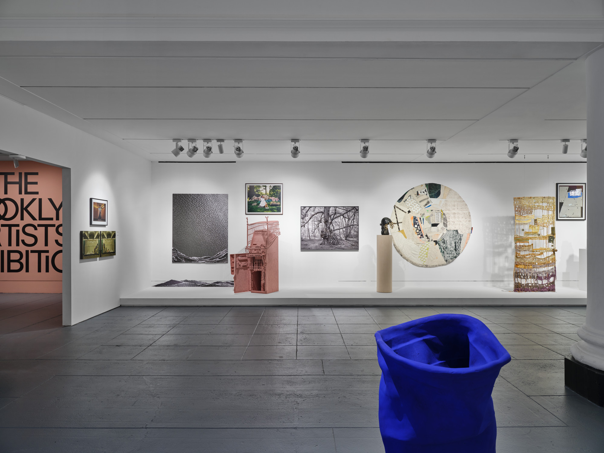 Wide-angle view of the interior of a museum gallery space with varied types of artworks in front of and hung on the wall
