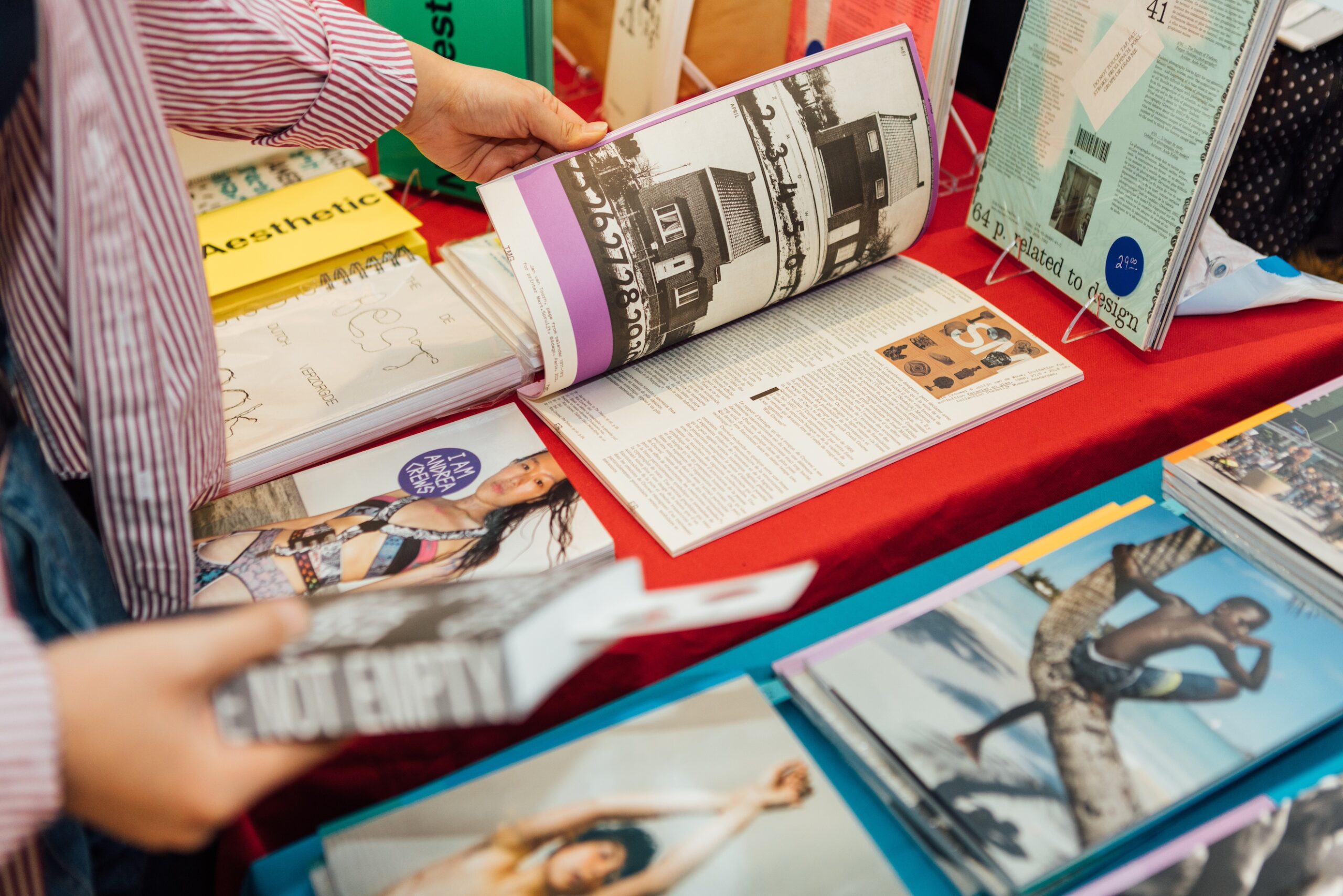 Close-up of someone’s hands paging through a book displayed on a table with other printed materials