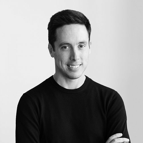 Black-and-white image of Ferraro, who has short, dark hair, wearing a black shirt and smiling at the camera