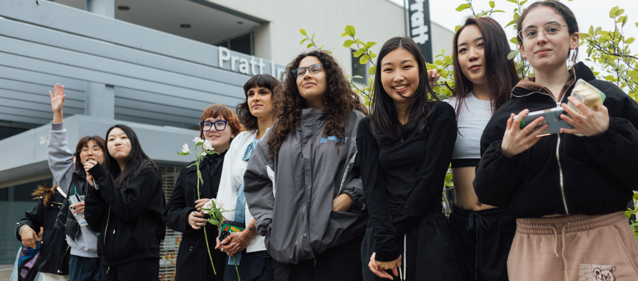 A group of students standing in front of one of the Pratt Institute buildings.