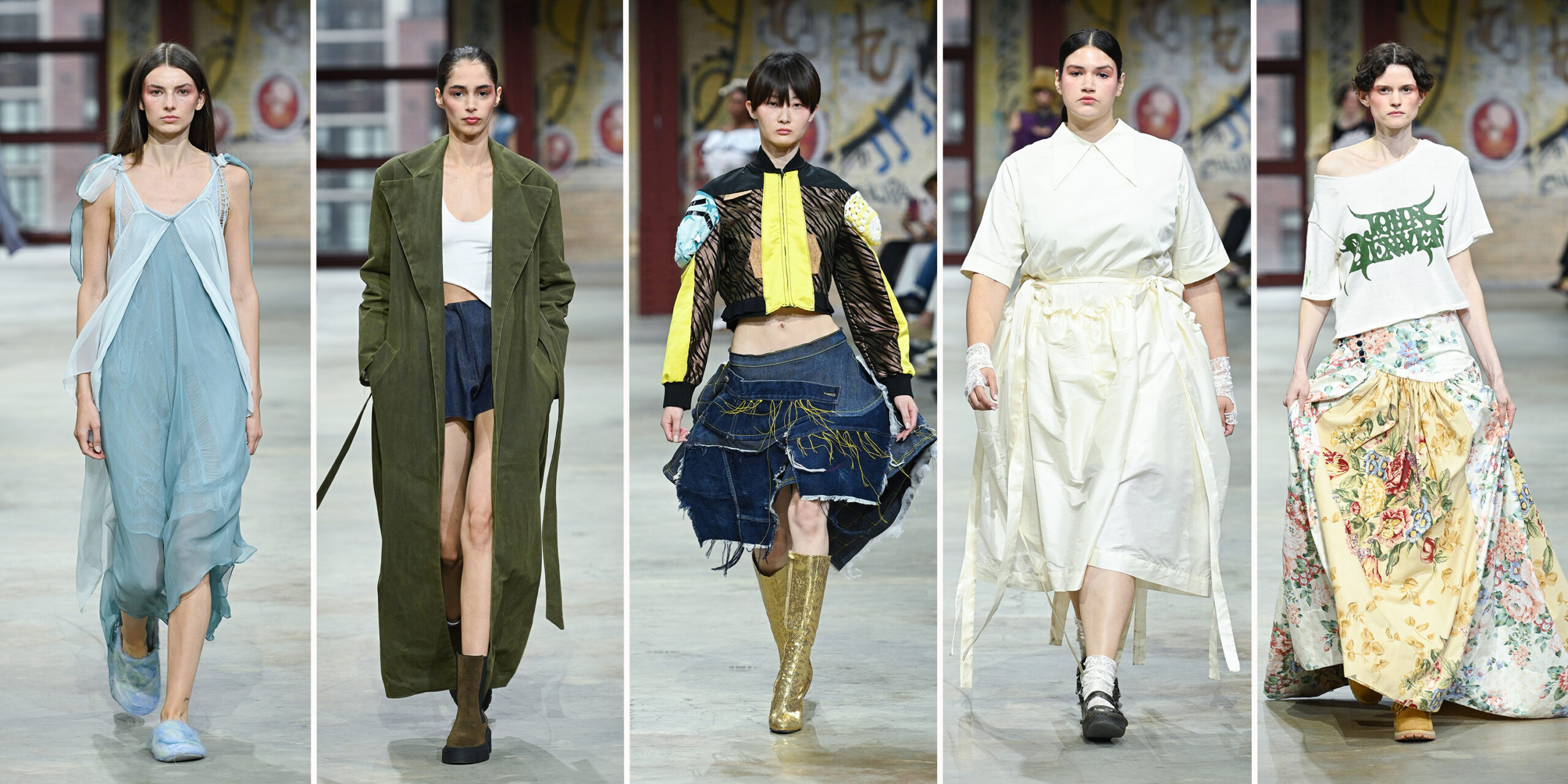 A collage of five runway models walking at a fashion show, with an urban, graffiti-covered backdrop. From left to right: The first model wears a sheer, flowing pale blue dress with layered chiffon and ribbon-like shoulder ties, paired with pastel tie-dye slippers. The second model wears a white crop top and dark mini skirt under a long, olive green coat with a belt. The outfit is completed with brown boots and a sleek hairstyle. The third model showcases a bold, cropped bomber jacket in black, yellow, and animal print with sculptural padded elements on the sleeves. It’s paired with an asymmetrical, deconstructed denim skirt featuring yellow stitching and raw edges, and tall, glittery gold boots. The fourth model wears a cream-colored midi dress with a wide, angular collar and cinched waist, accessorized with lace gloves and ankle socks paired with black Mary Jane-style shoes. The fifth model wears an off-the-shoulder white cropped tee with green gothic text, styled with a dramatic floor-length skirt made of richly patterned floral fabrics in a patchwork style. The look is completed with chunky sandals.
