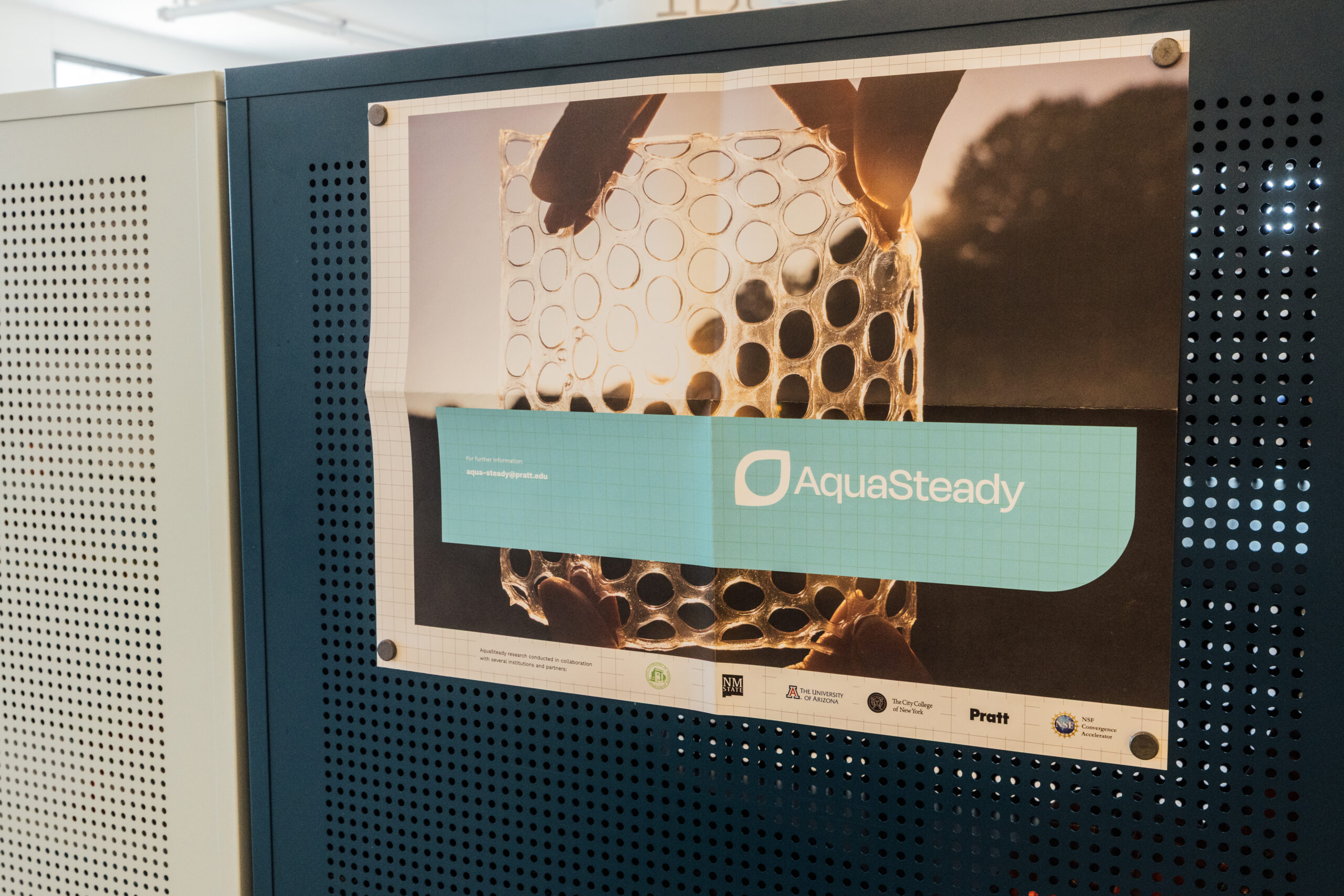 Poster pinned to a blue perforated board promoting