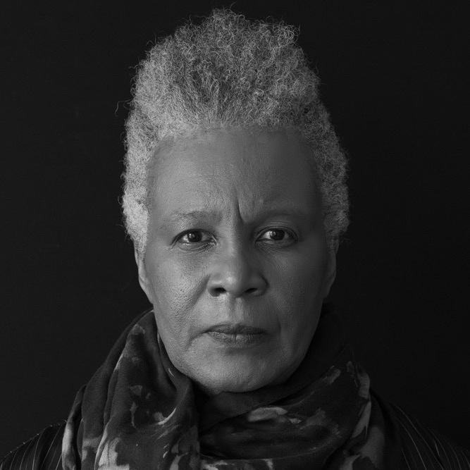 Black and white photography of Claudia Rankine looking straight into the camera intensely.