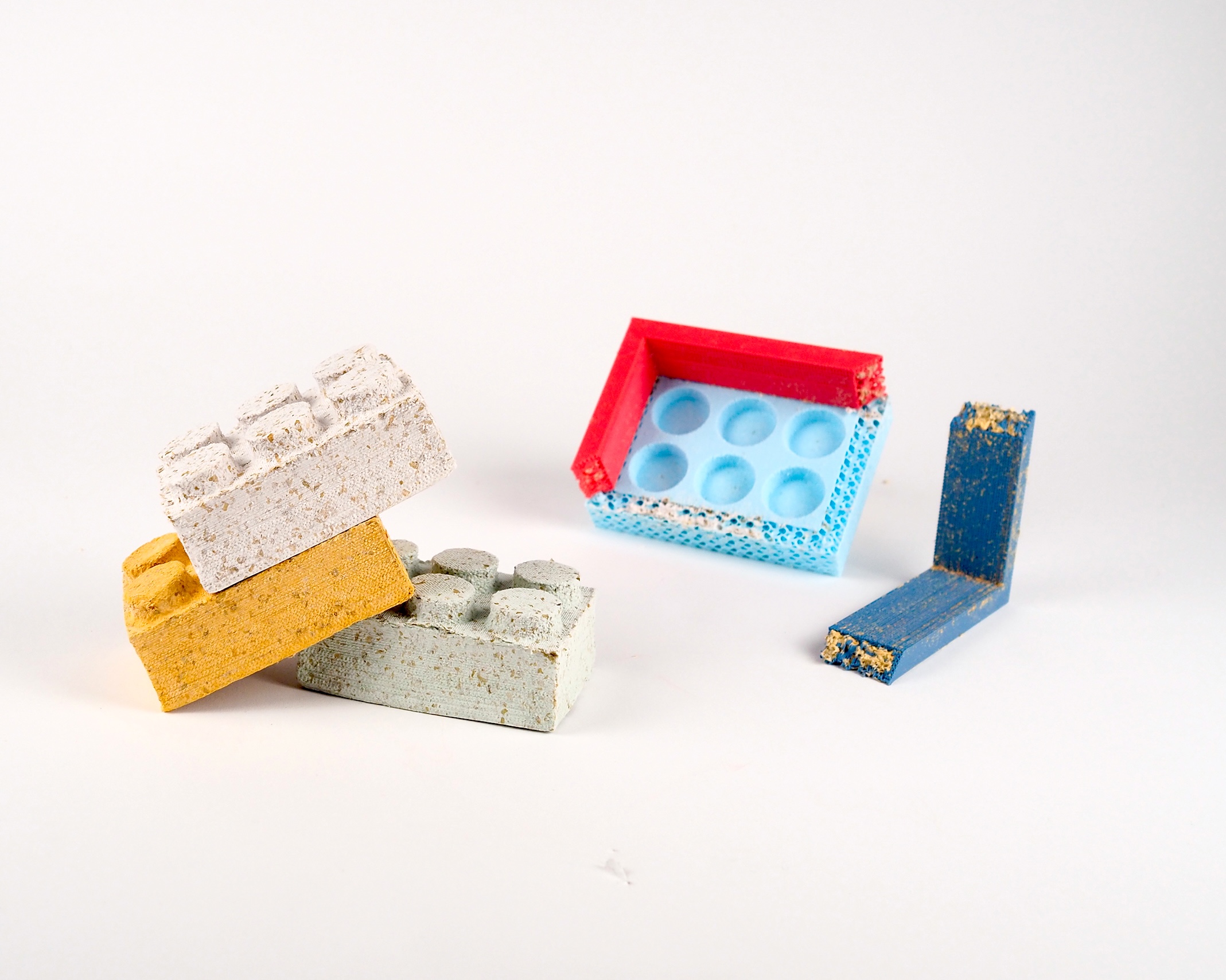 A stack of white, yellow, and gray paper bricks placed beside a blue and red brick mold