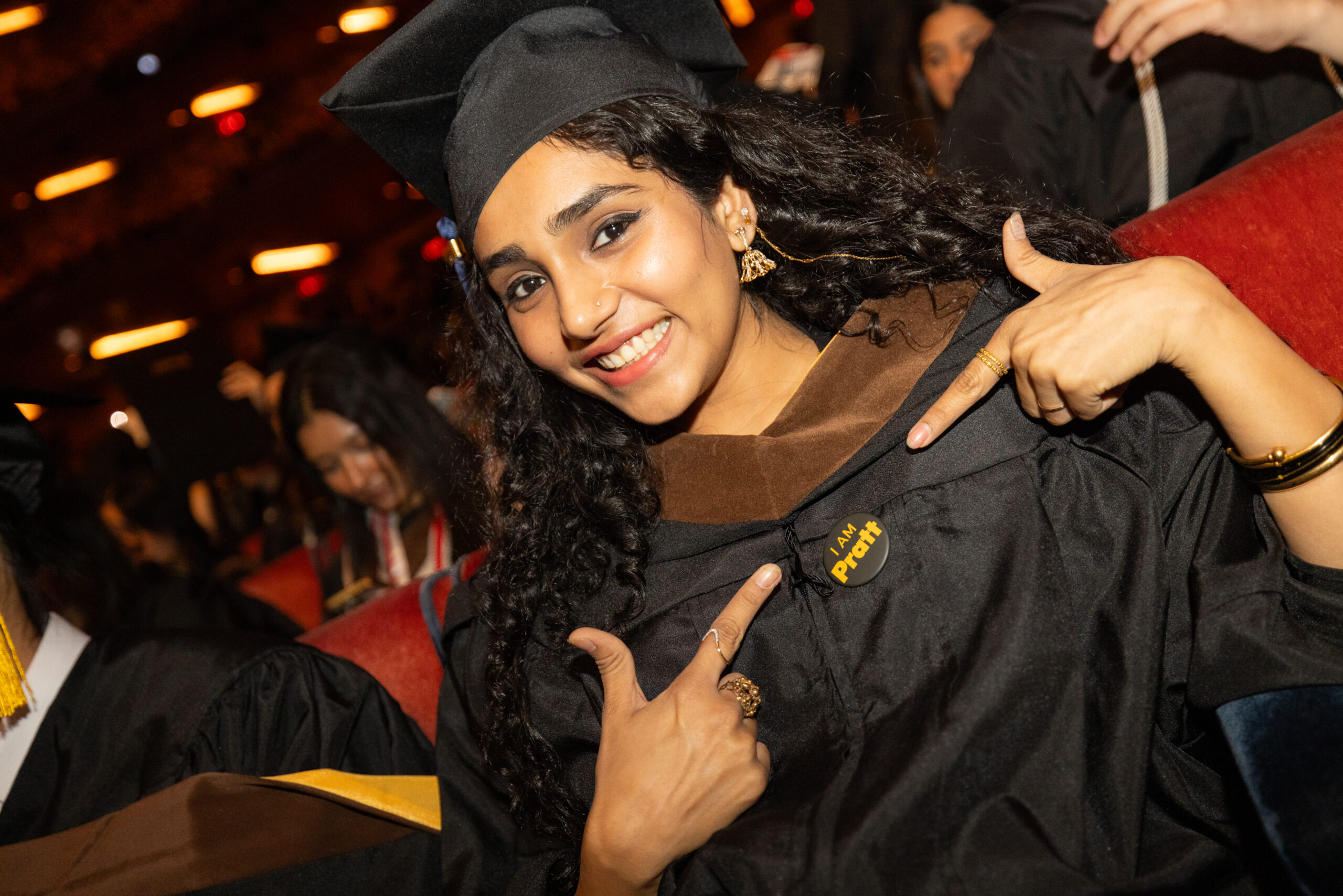 A graduate points proudly to a button on her gown that reads