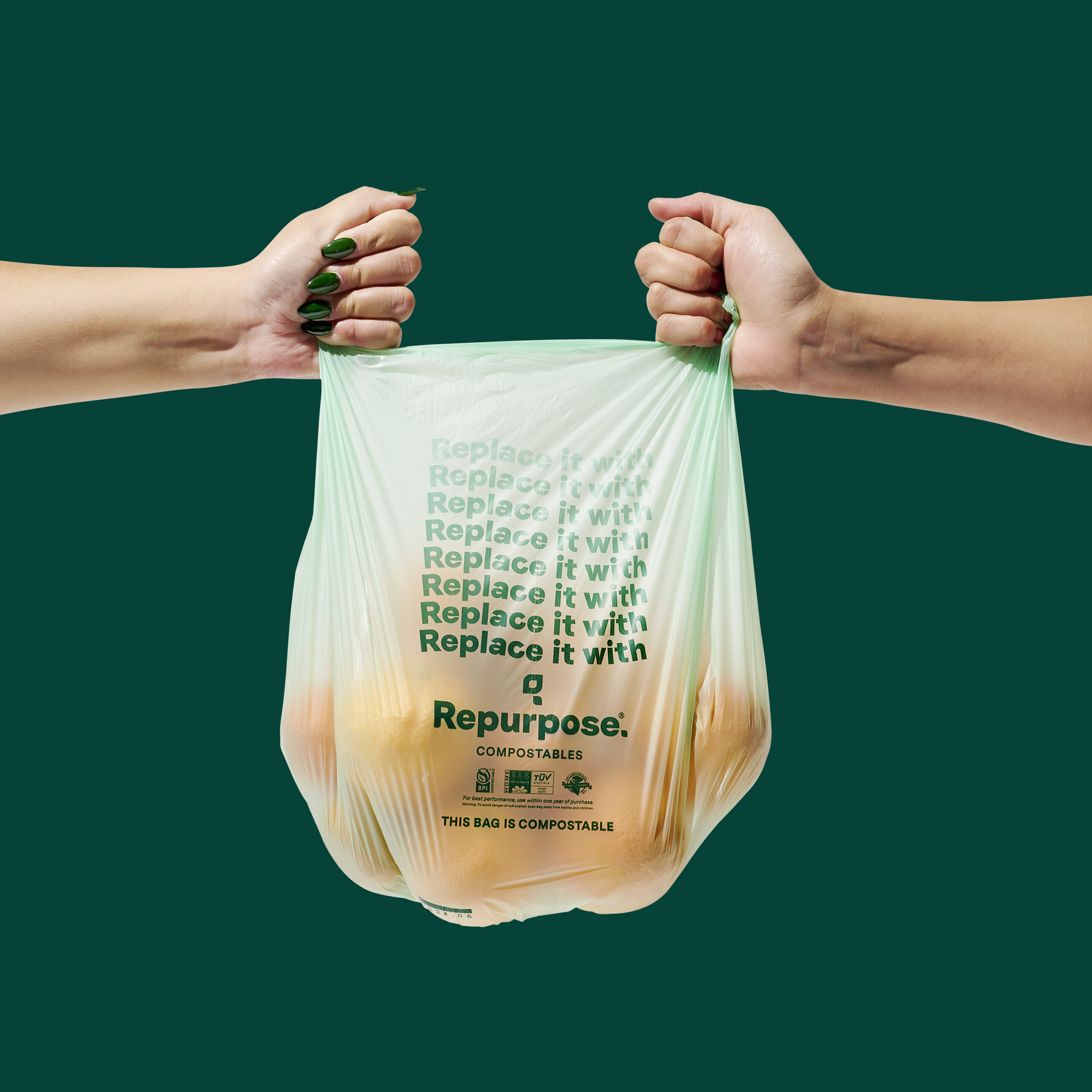 A slightly transparent green composting bag with the layout of text that reads “Replace it with Repurpose” mimicking the design of a plastic grocery bag, held up on either side by two hands