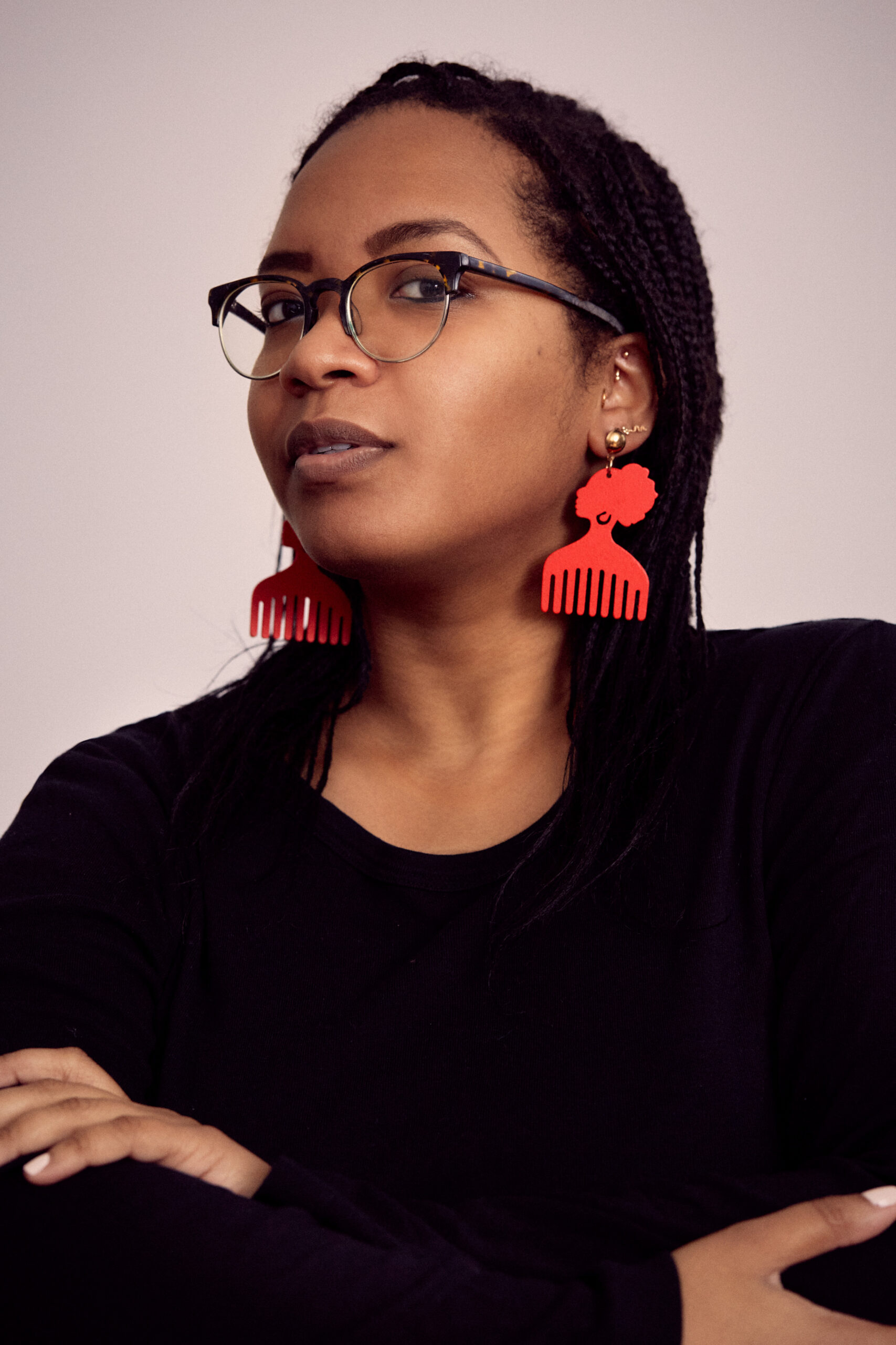 Headshot of Deepa Shanbhag, wearing glasses, red earrings with a comb-shape design, and black top and blazer
