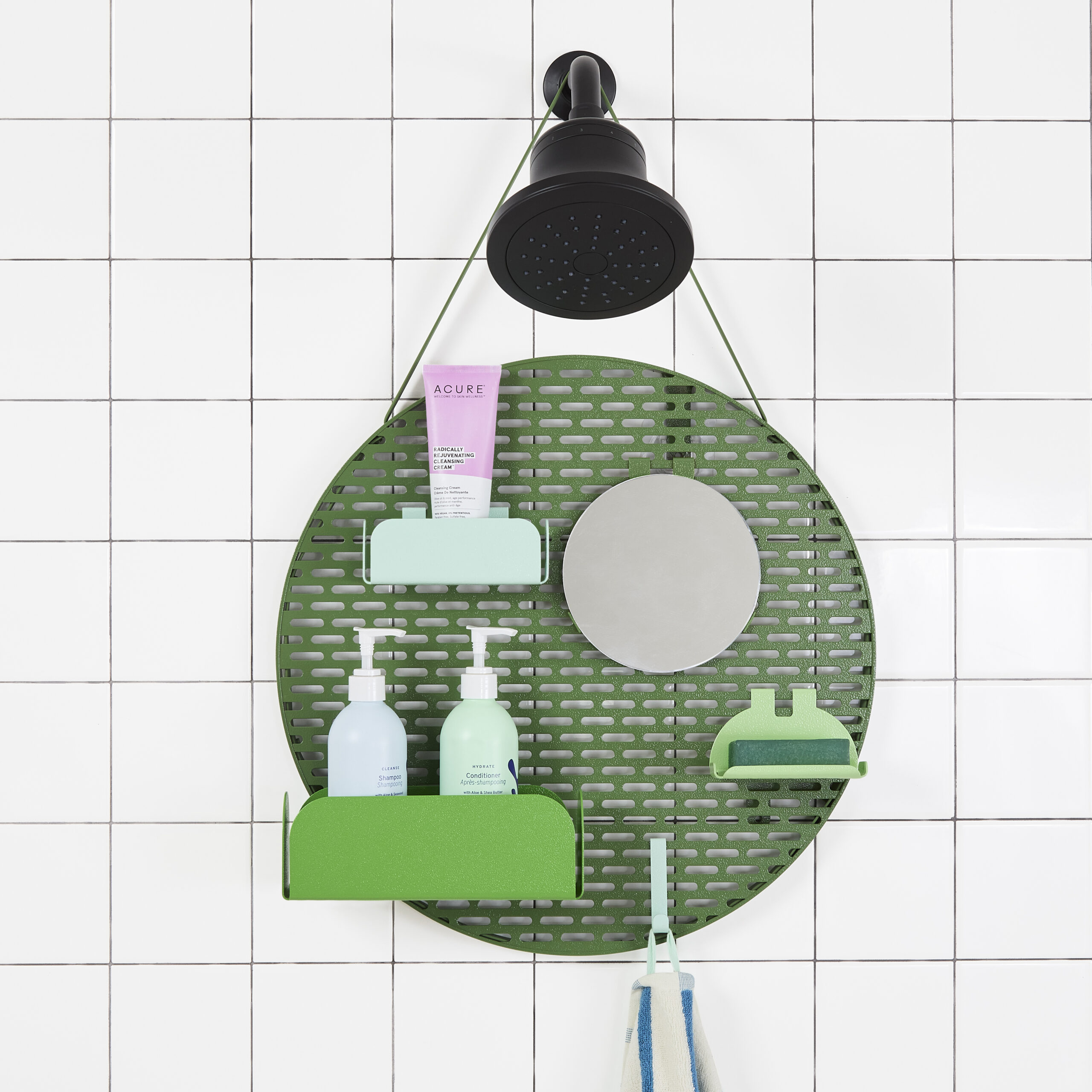 Circular green shower rack with a pegboard-like design with moveable shelves, hanging on a black showerhead against white tile