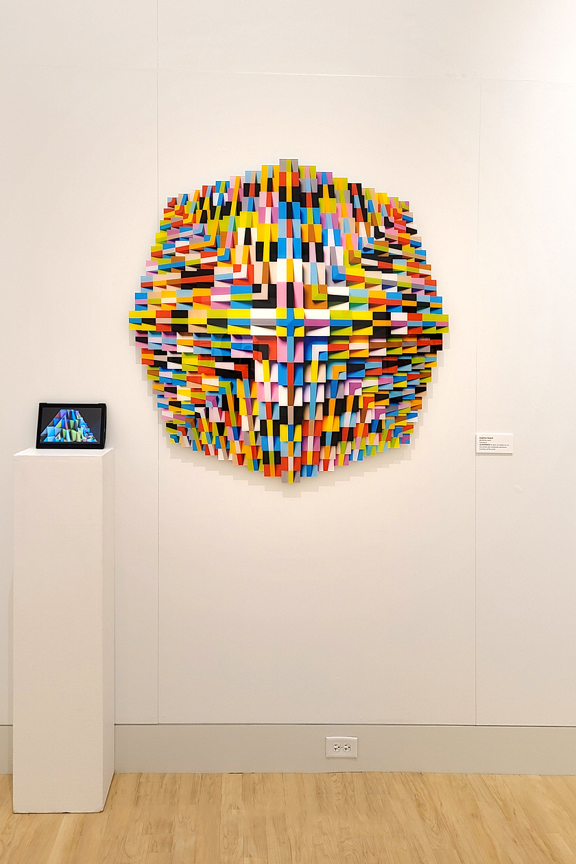 Installation shot of sculpture in which geometric shapes build upon each other to create a multi-sided, pyramid-like structure as seen from an aerial perspective