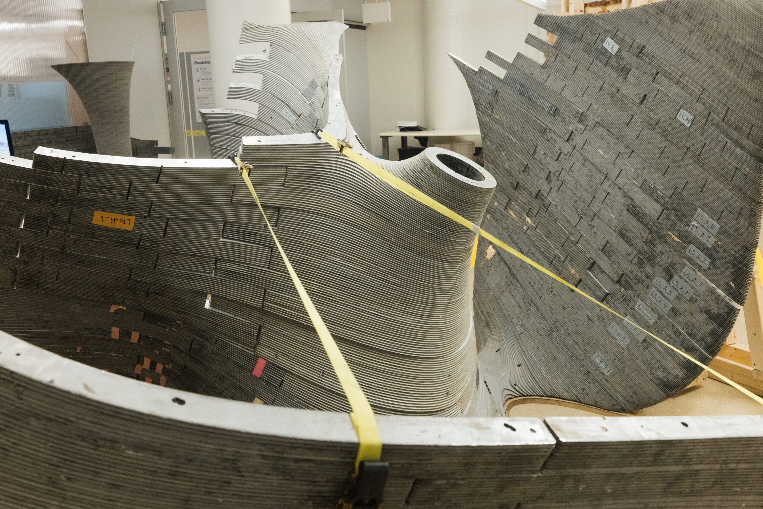 A metal work-in-progress sculpture, held together with tension straps.