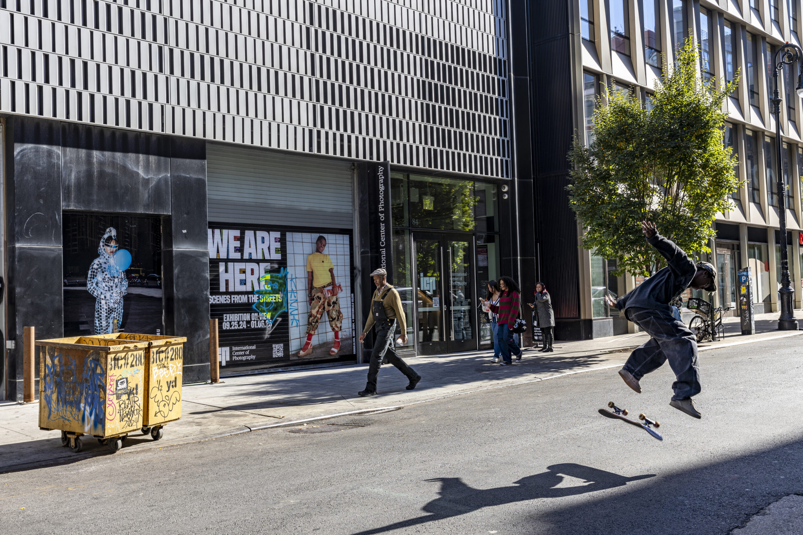 A skateboarder does a trick on the street in front of the International Center for Photography in New York City.