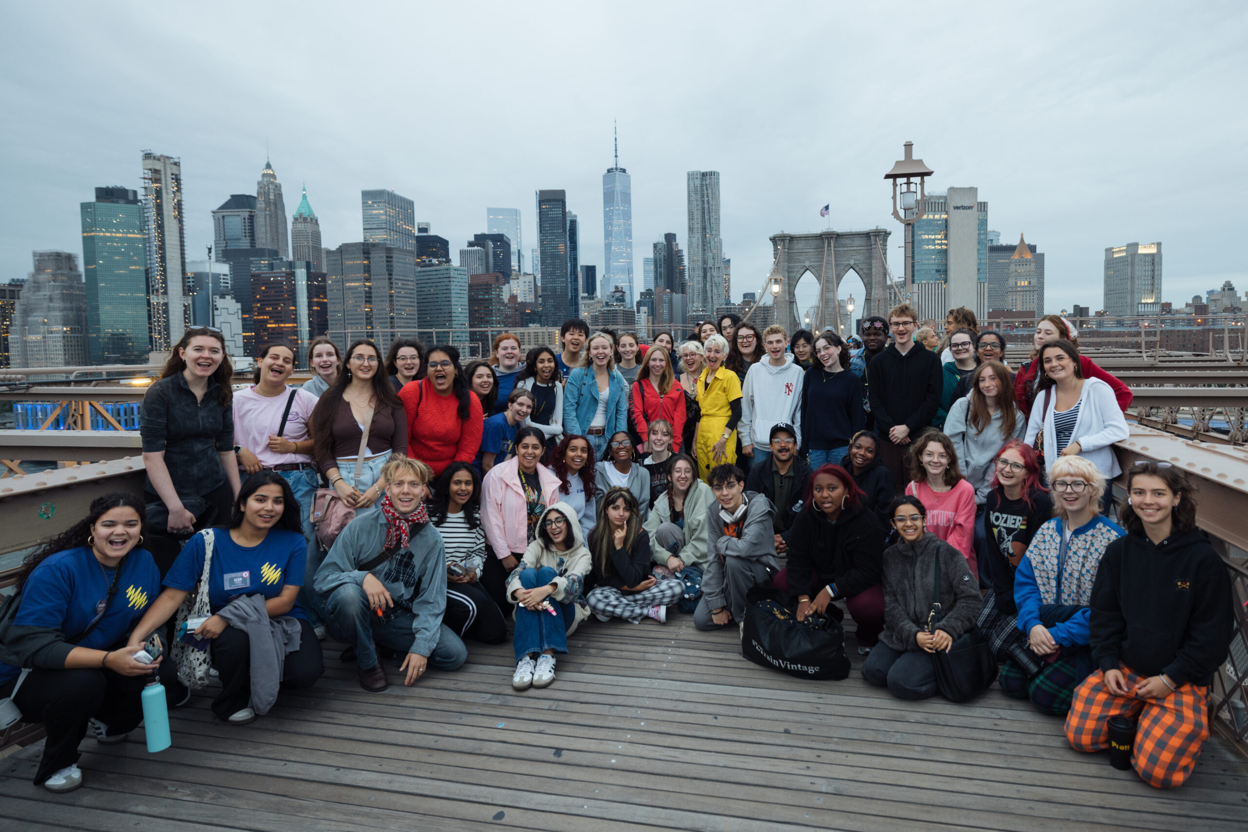 A crowd of people pose for a photo on the Brooklyn Bridge in the early morning.