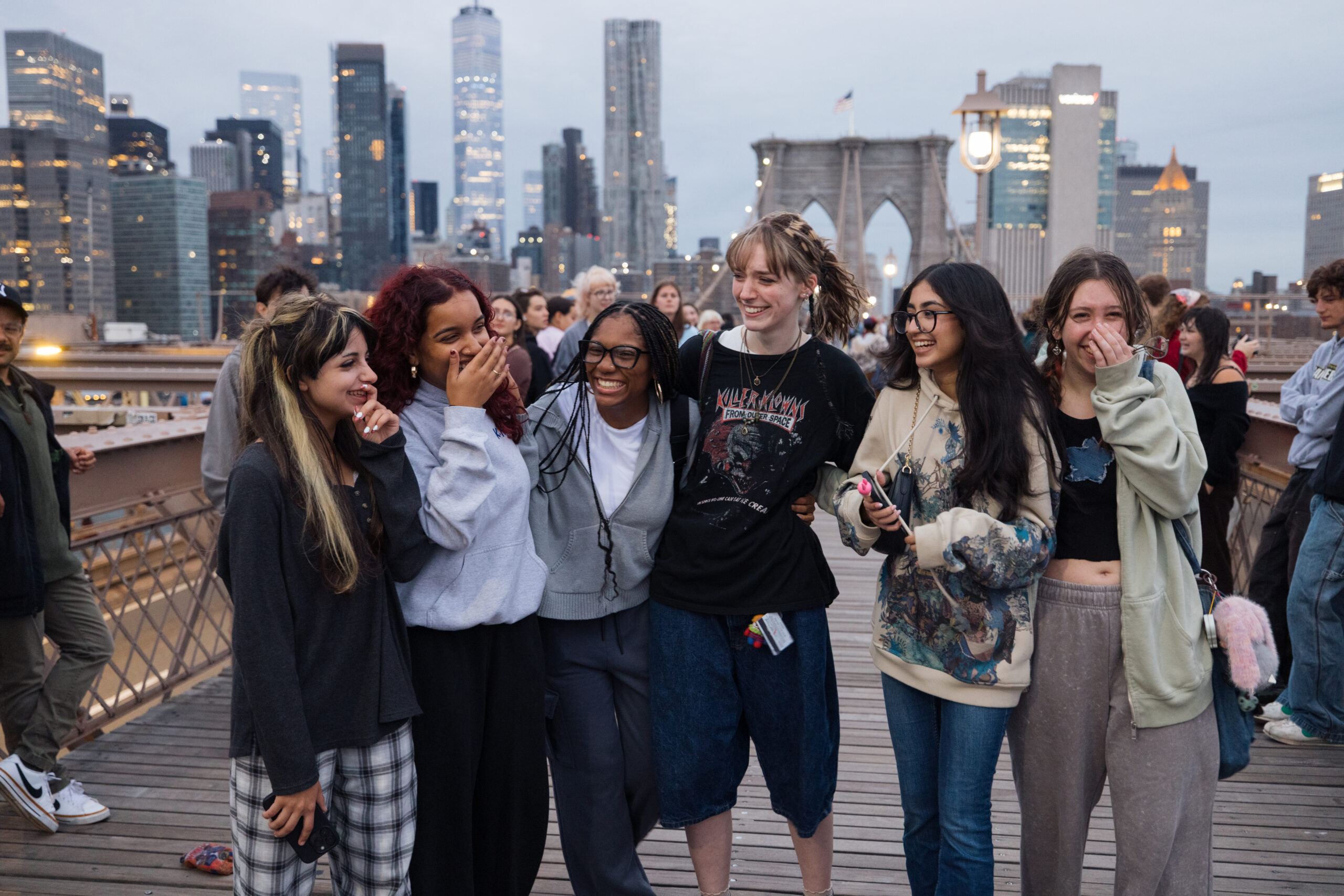 A group of friends share a laugh on the Brooklyn Bridge as the sun comes up.