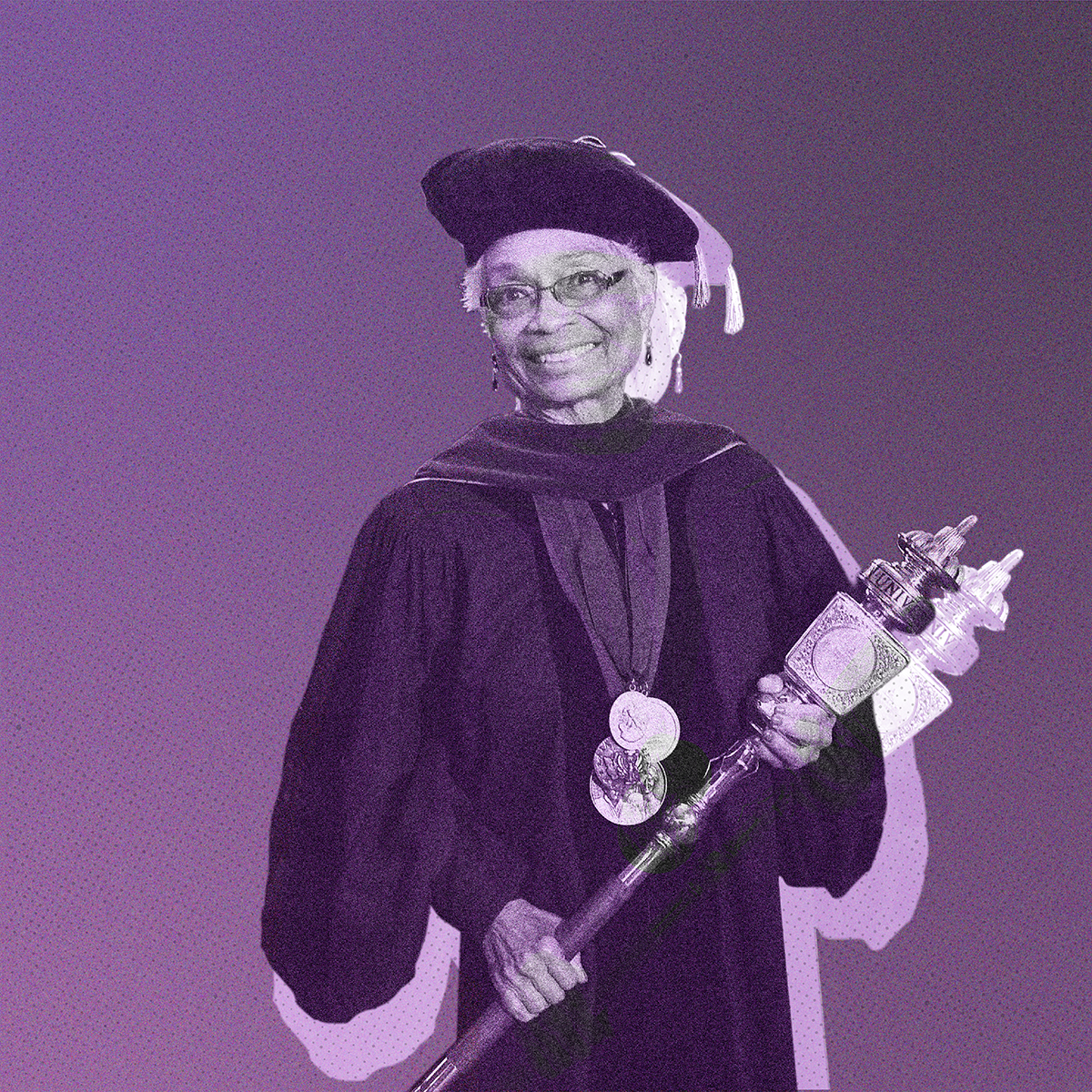 Sharon Sutton stands in academic regalia, wearing a cap and gown with medals, smiles while holding a ceremonial mace against a purple background.
