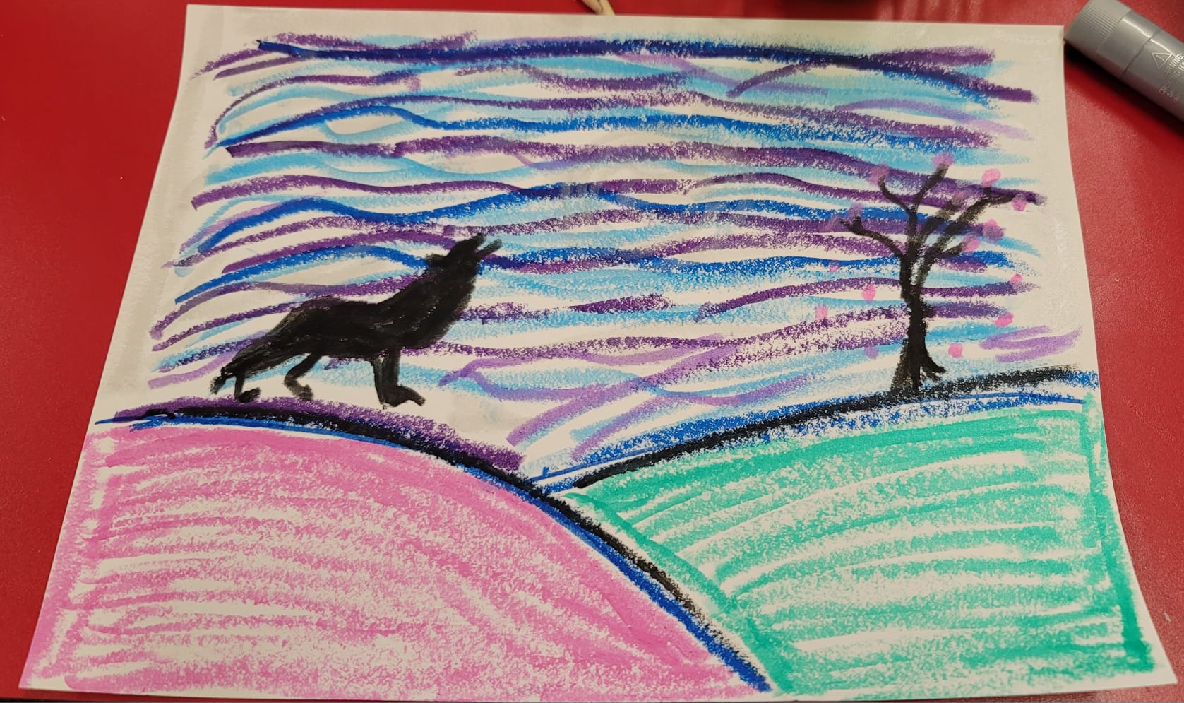 A colorful crayon drawing of a wolf howling on a hill, near a tree.