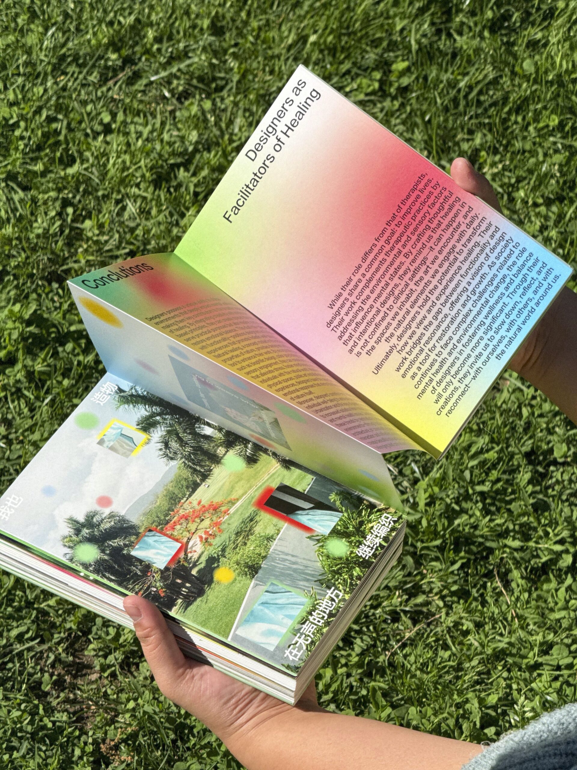 Hands holding an open gradient-colored book on grass, showing text titled 'Designers as Facilitators of Healing' alongside vibrant images and Chinese characters.