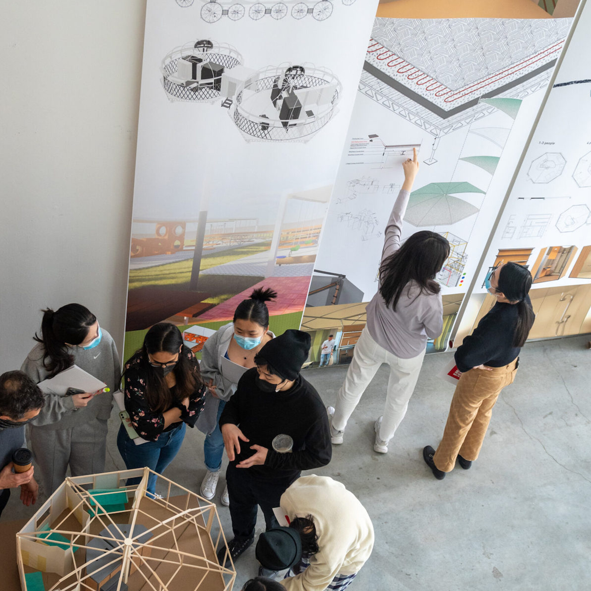 Students and faculty at exhibit with posters and models