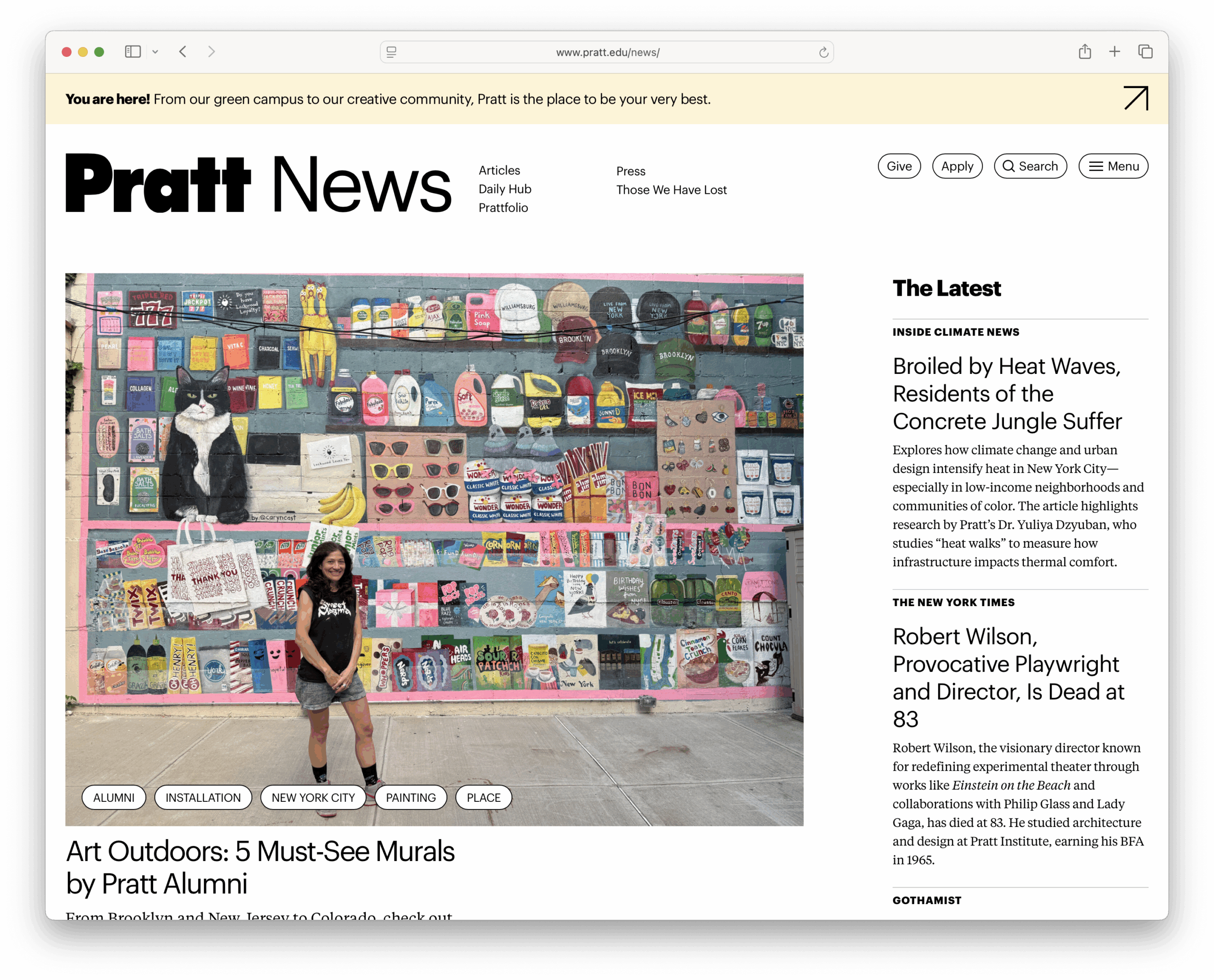 A screenshot of the Pratt website's News page. There's a large photograph on the page. A woman stands in front of a colorful mural featuring various images and text, including depictions of food and drink items, New York-themed elements, and abstract designs. The mural displays a wide range of vibrant colors. She is wearing a black graphic t-shirt and denim shorts, smiling at the camera. The scene is set in an urban environment, likely in New York City.
