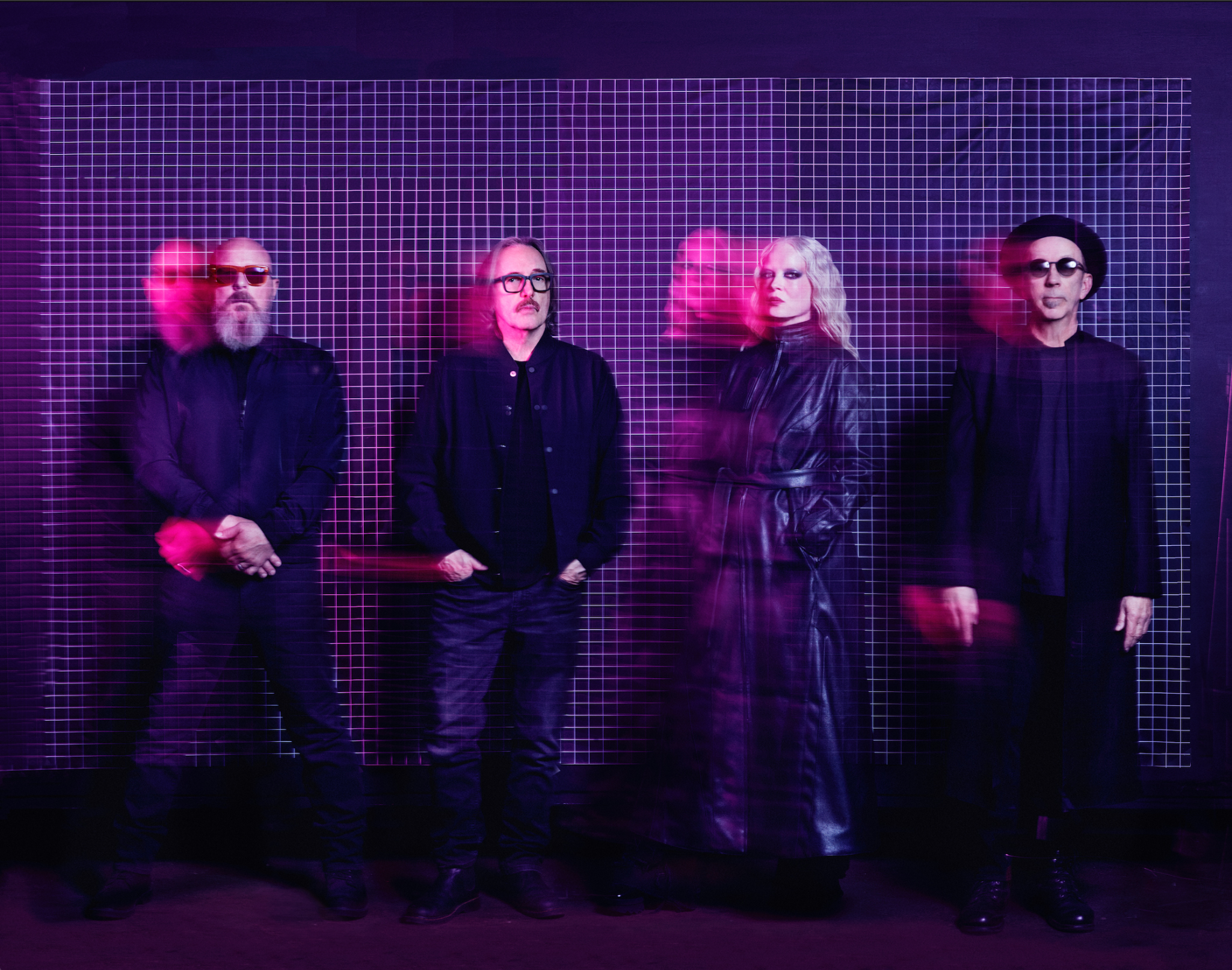 Four bandmates pose against at gridded wall in pink light with a strobe effect