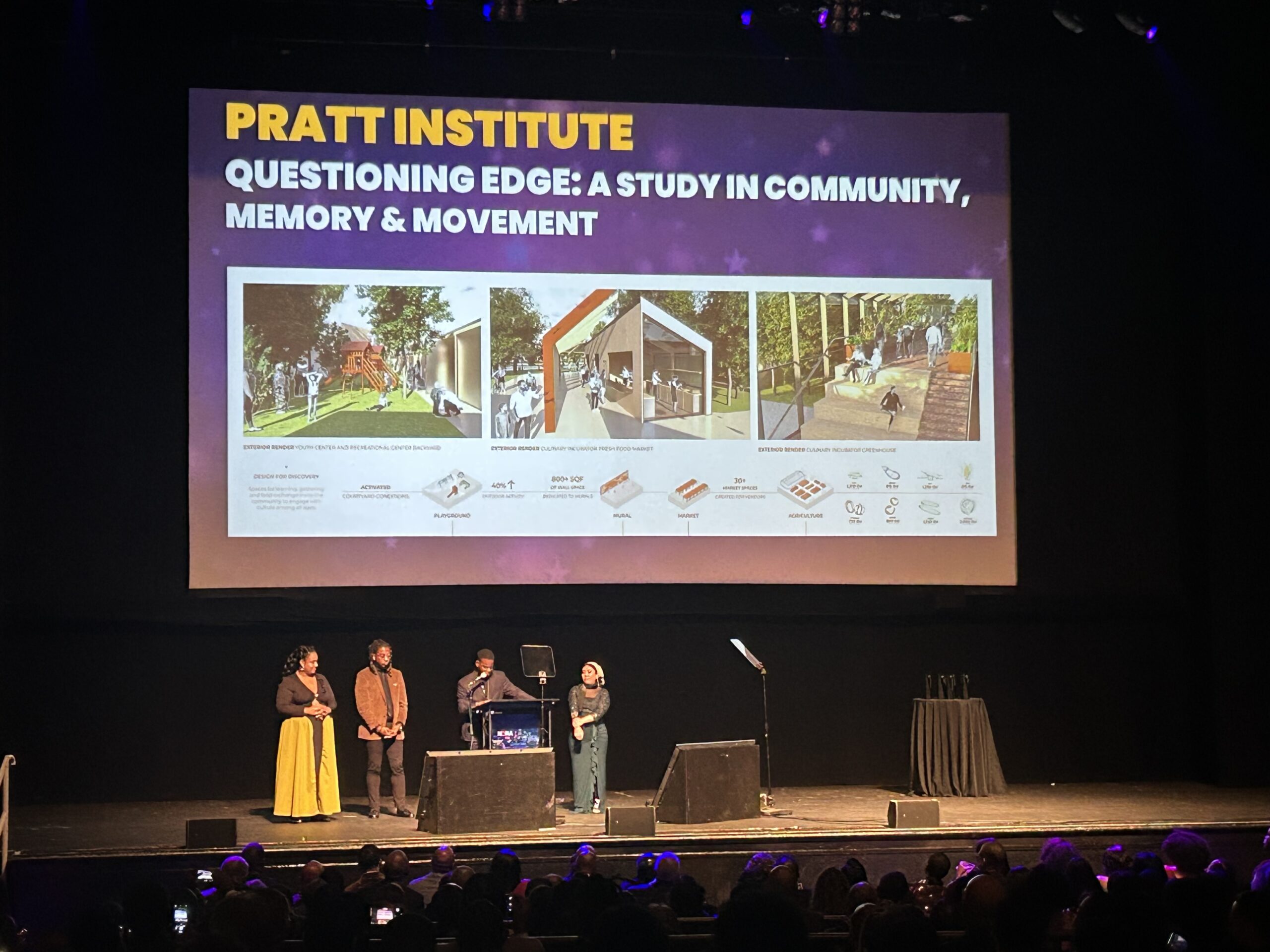 A stage presentation at an event features a large screen displaying the title "Pratt Institute: Questioning Edge: A Study in Community, Memory & Movement." Below the title are images related to the study, depicting outdoor community spaces. Three people stand on stage in front of the screen, two women and one man, while attendees are seated in the foreground, facing the stage.