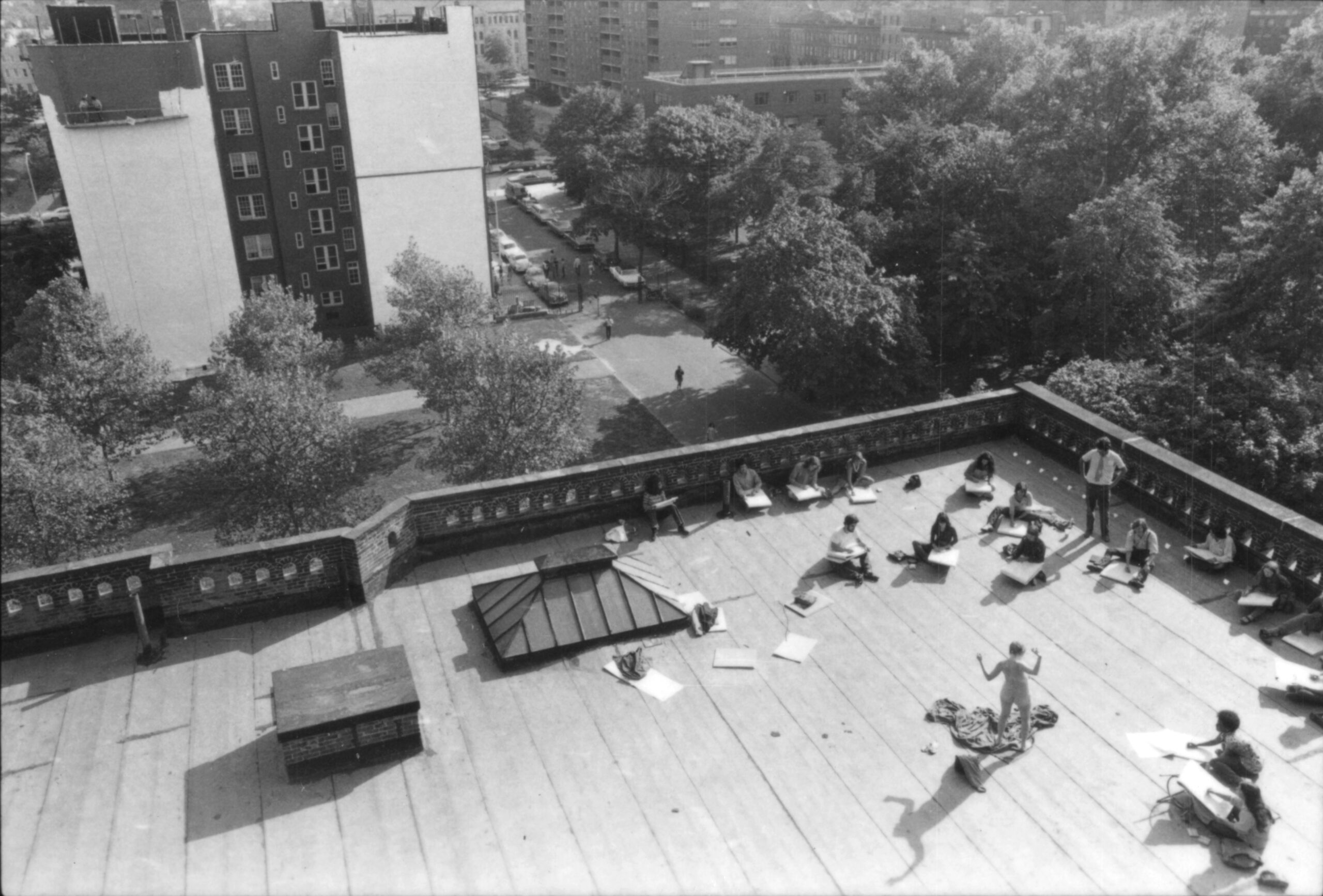 Students sketch a live nude model on a rooftop.