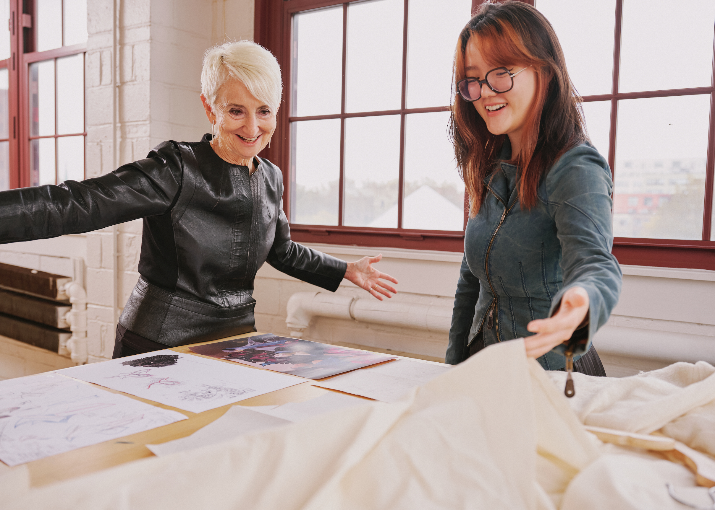 President Frances Bronet in a studio at Pratt with a student, both looking at a project laid out on a table