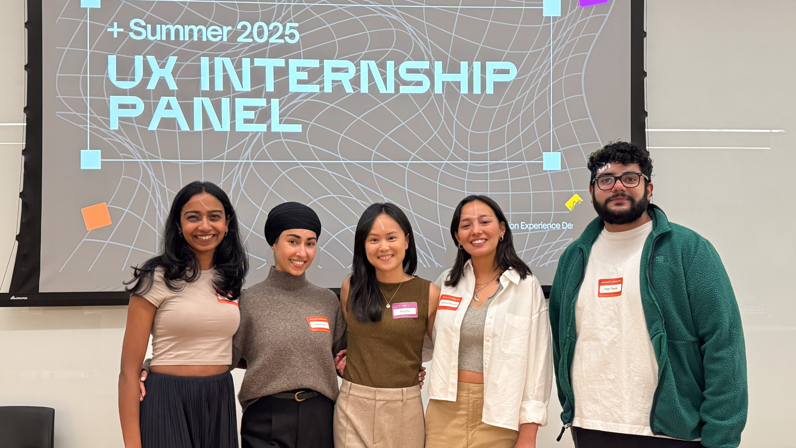 Five individuals stand in front of a screen displaying the text "+ Summer 2025 UX INTERNSHIP PANEL." They are posing together, smiling, and wearing casual clothing. Each person has a name tag. The background features a geometric design with various shapes in light colors.