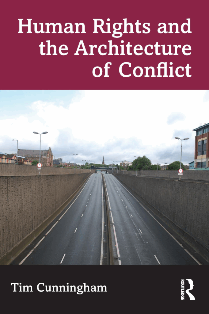 The cover of “Human Rights and the Architecture of Conflict” shows an empty road bisecting a community with tall walls on either side.
