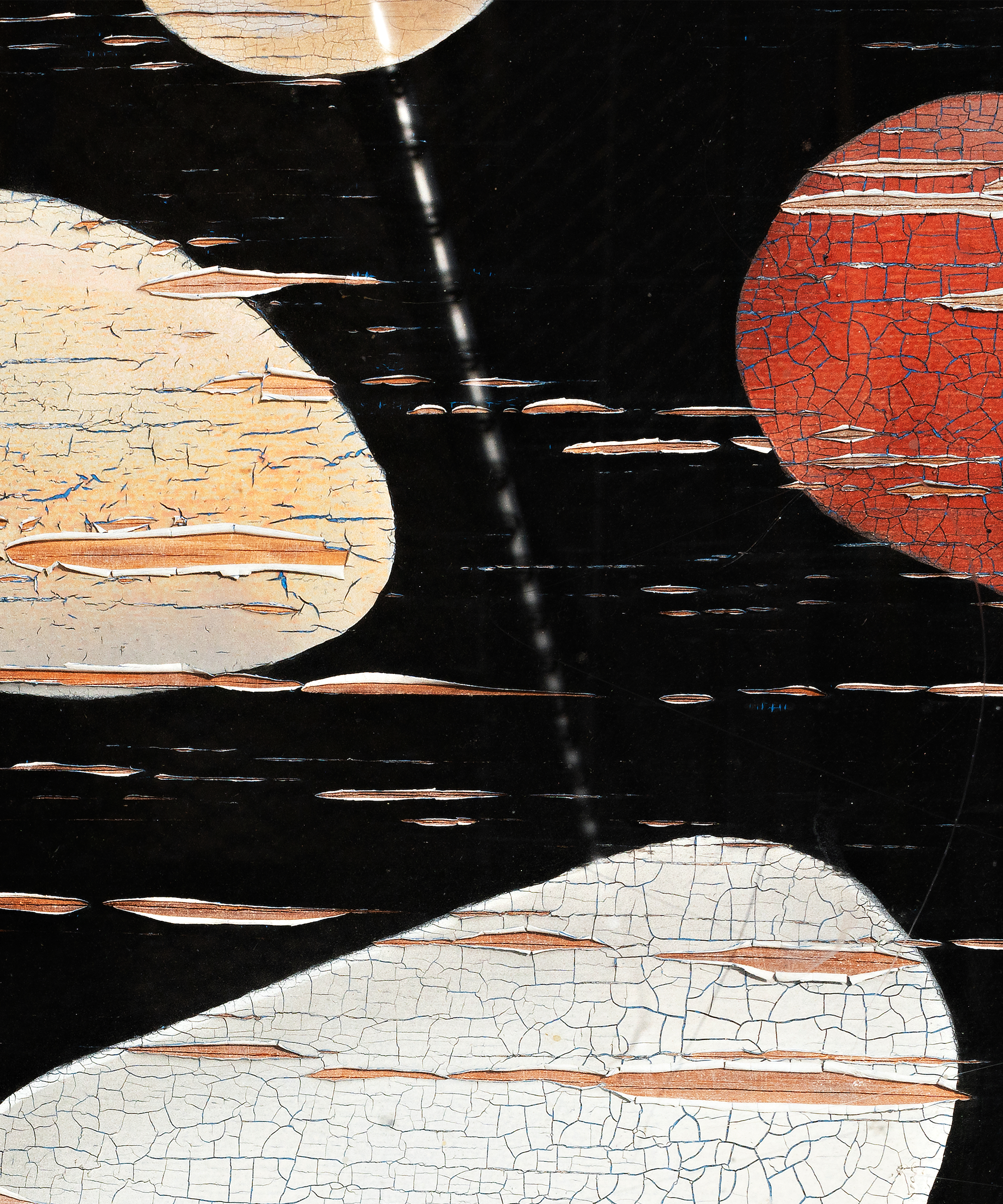 Peeling paint that depicts red, tan, and white shapes against a black background reveals wooden material beneath.