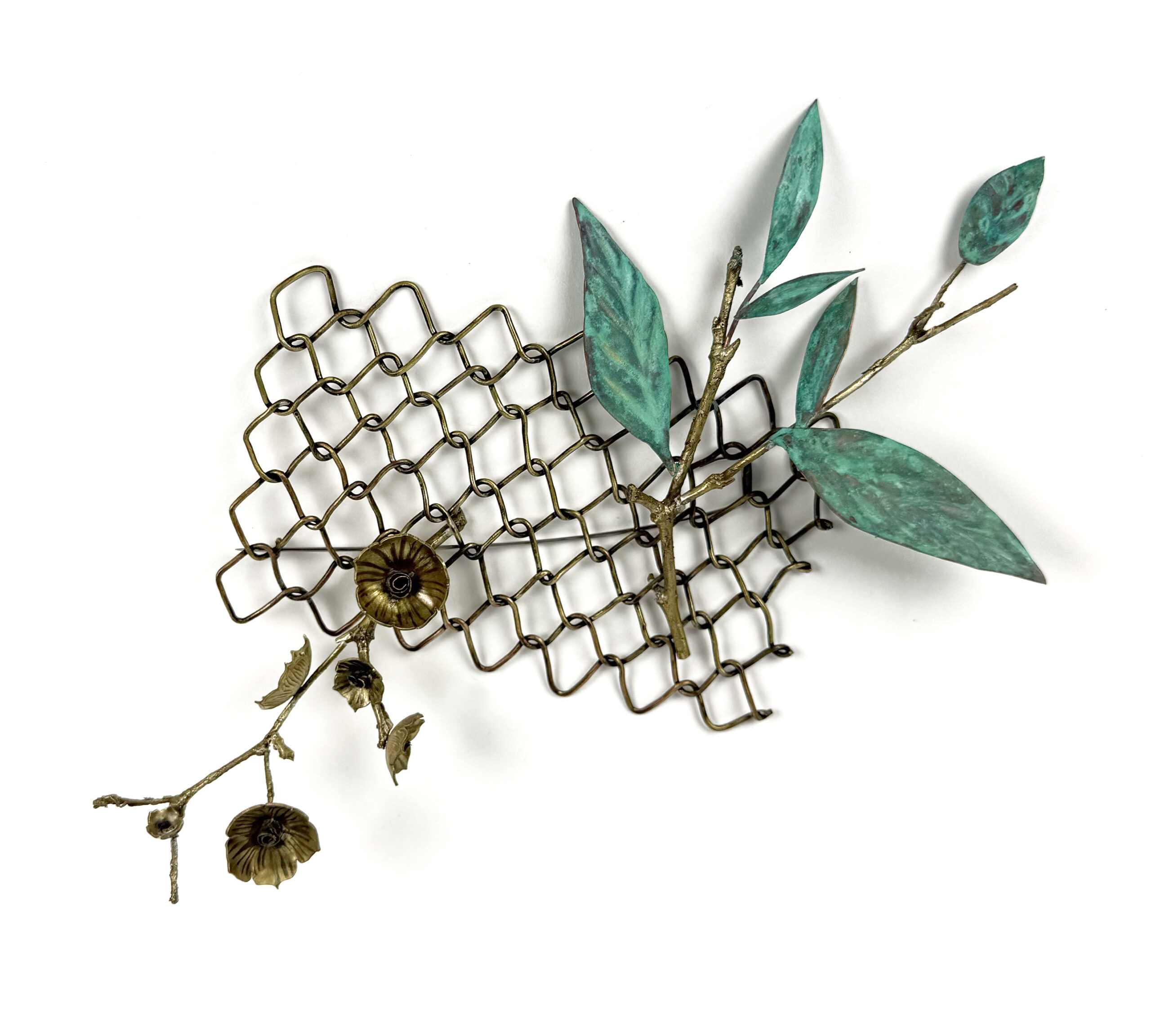 A decorative arrangement featuring a honeycomb-shaped metal mesh in a bronze tone, with two green leaves and a branch with three brownish flowers attached. The leaves are painted in shades of teal, while the flowers have a metallic finish, adding texture and visual interest to the composition. The background is plain white, emphasizing the art piece.