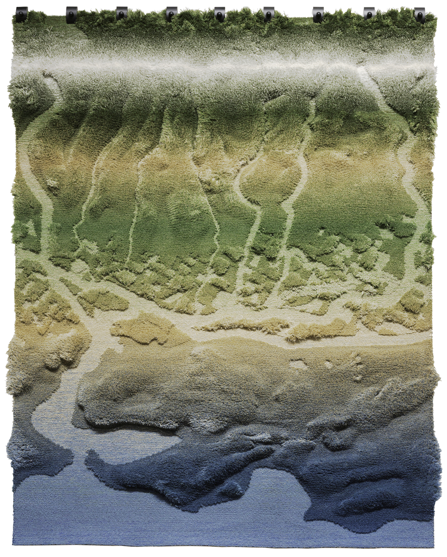 Large textile wall hanging with a sculptural, tufted surface forming an abstract landscape. The rug transitions vertically from deep blue at the bottom to sandy beige, then olive and dark green at the top, resembling waterways, erosion patterns, and vegetation seen from an aerial perspective. The piece is mounted with visible hardware along the top edge against a neutral background.