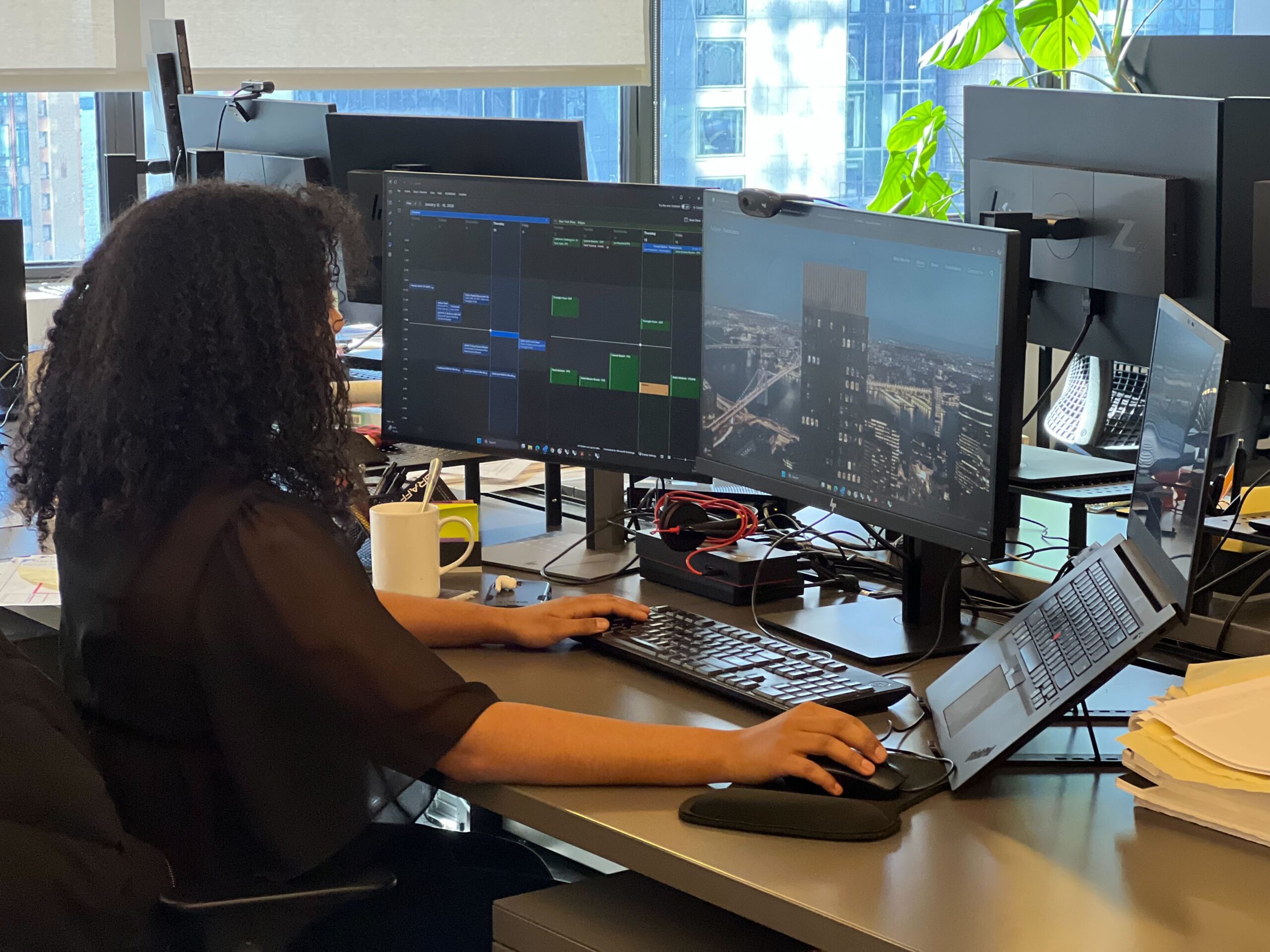 Alumna Catherine Chattergoon works at a desk while using multiple monitors.
