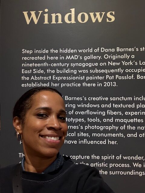 Alumna Vonetta DeVonish is pictured from the shoulders up in front of a gallery display description titled “Windows.”