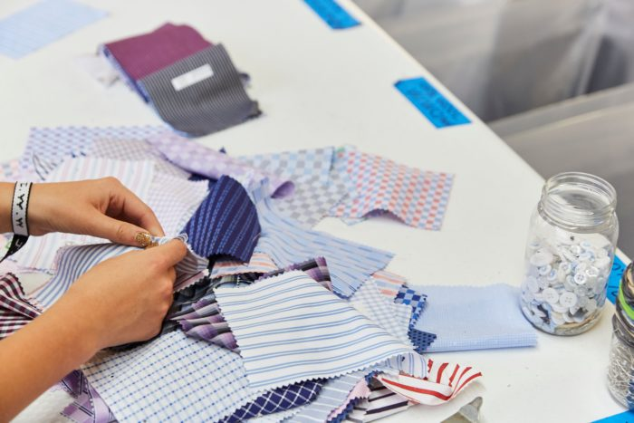 Image shows a pair of hands sorting through blue fabric on a white table