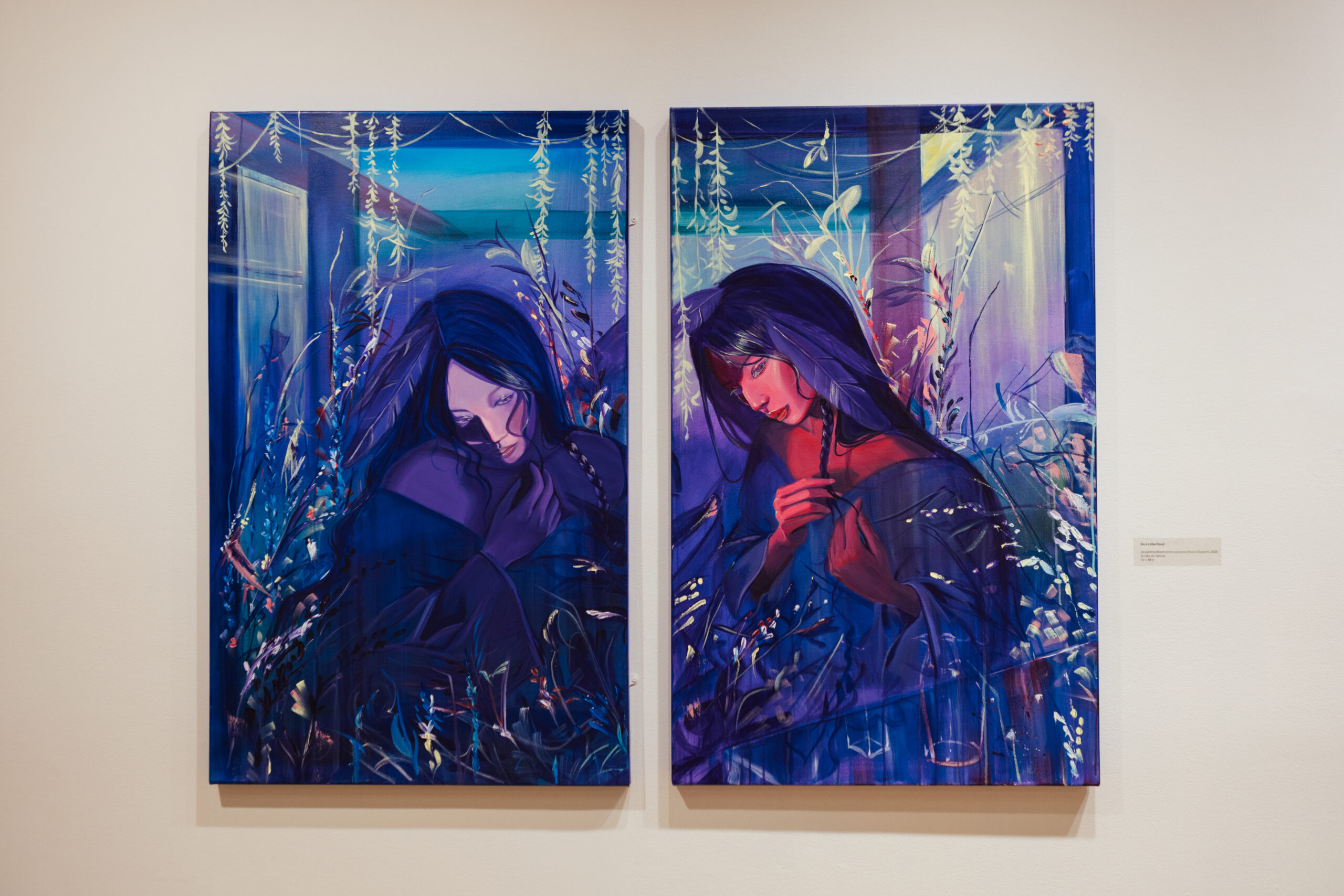 Two connected paintings depict two people with long dark hair, set against a backdrop of blue and purple hues. Each person appears contemplative, with one partially turned away and the other gently holding their hair. The surrounding floral elements create an ethereal atmosphere, capturing a sense of introspection and emotion. The paintings are displayed on a white wall, with a small label visible beside the right artwork.