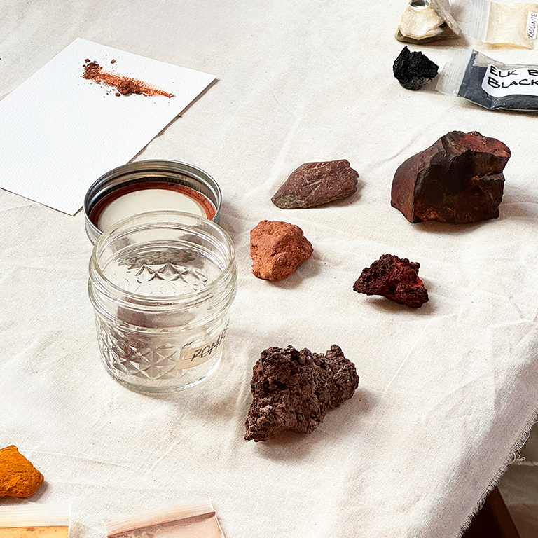 people painting with natural pigments using paintbrushes, plastic cups, palettes on a sheet of paper