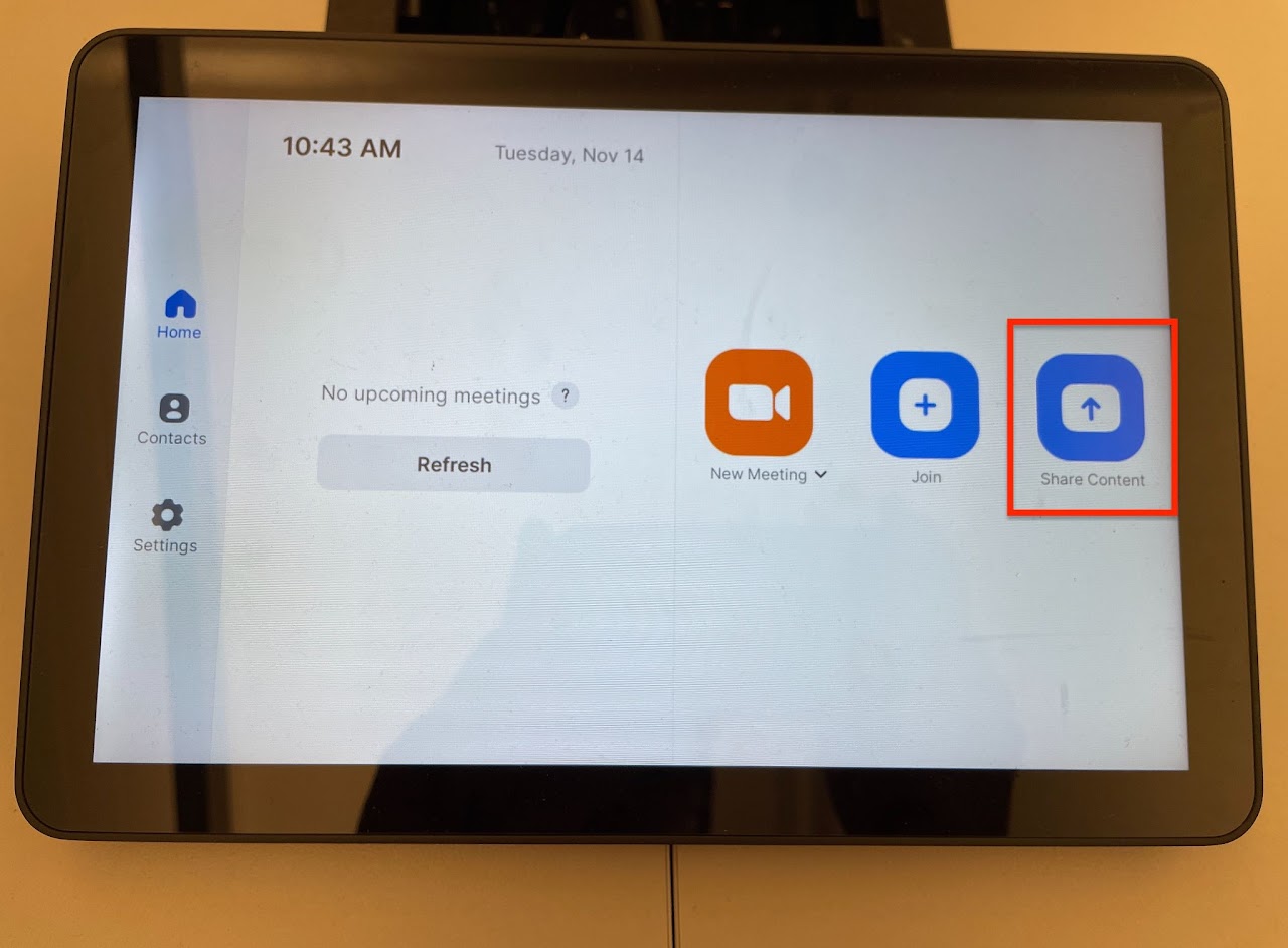 A tablet interface displaying a "Share Content" menu. It shows options to share from a desktop, iPhone/iPad, or using a Zoom app. The highlighted message indicates "Use Laptop HDMI" and mentions "Currently sharing locally." Below, there are buttons labeled "Share Screen," "Stop Sharing," and "Start Meeting," along with a sharing key and a volume slider. The bottom lists "Conference Room North."