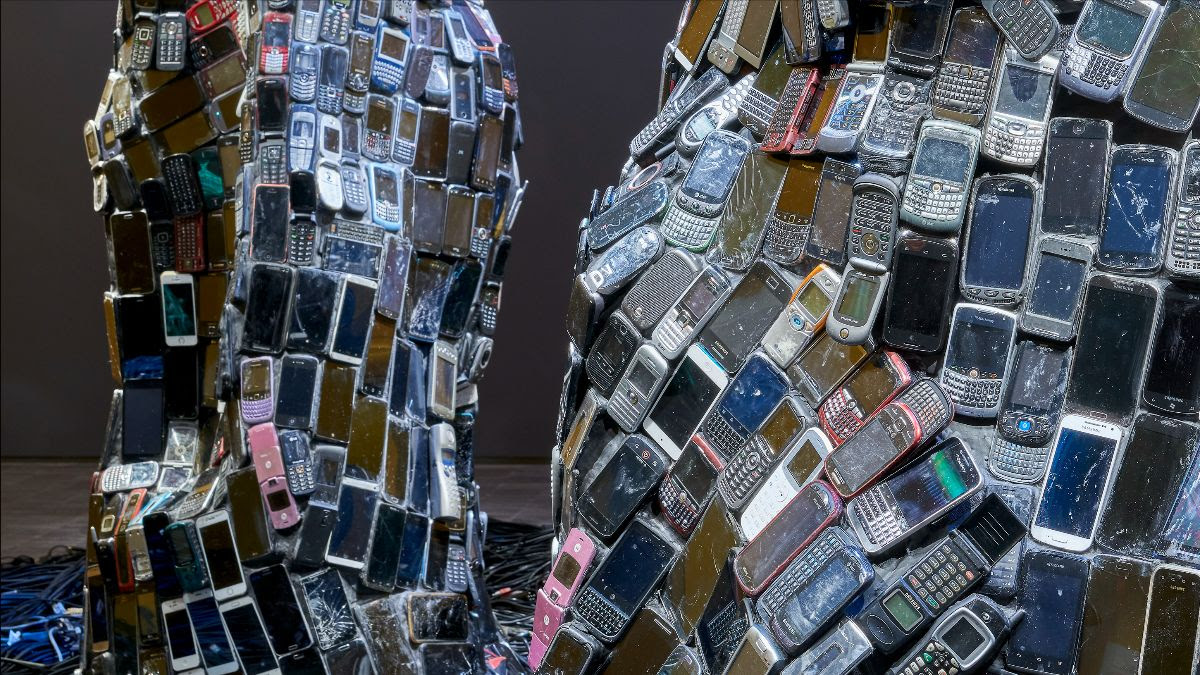 An abstract sculpture made from numerous old mobile phones, arranged in a mosaic pattern.