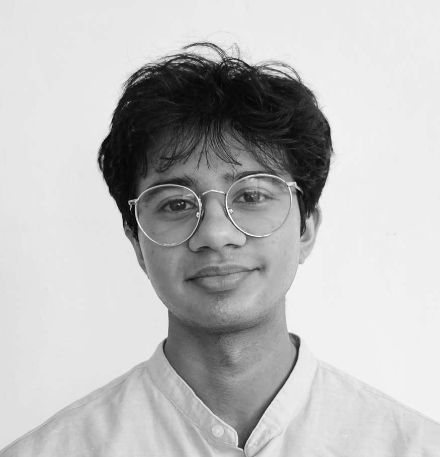 A young person with curly dark hair wearing round glasses and a light-colored shirt is smiling. The background is plain and white, creating a clean, minimalist look.